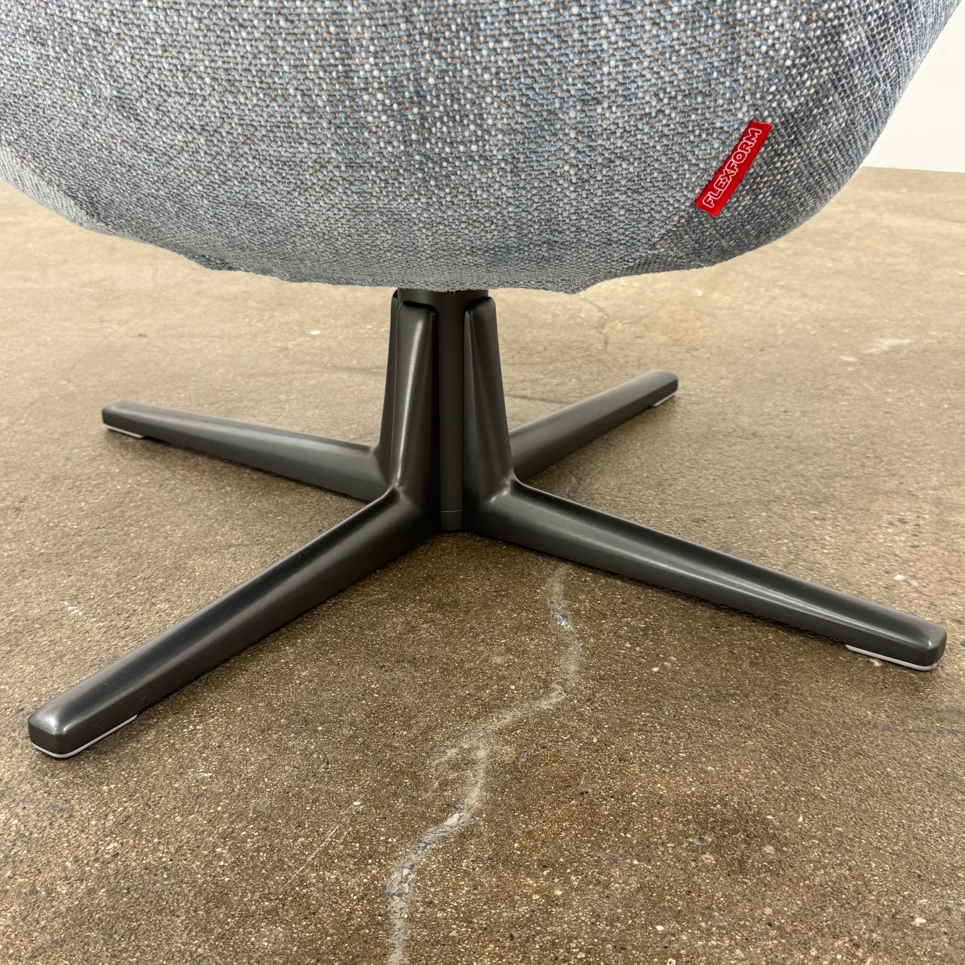 The Flexform Marlon Swivel Armchair and Ottoman, available with two covers, feature ergonomic design and black metal bases from Flexform, shown here in a modern gray finish against a plain white background.