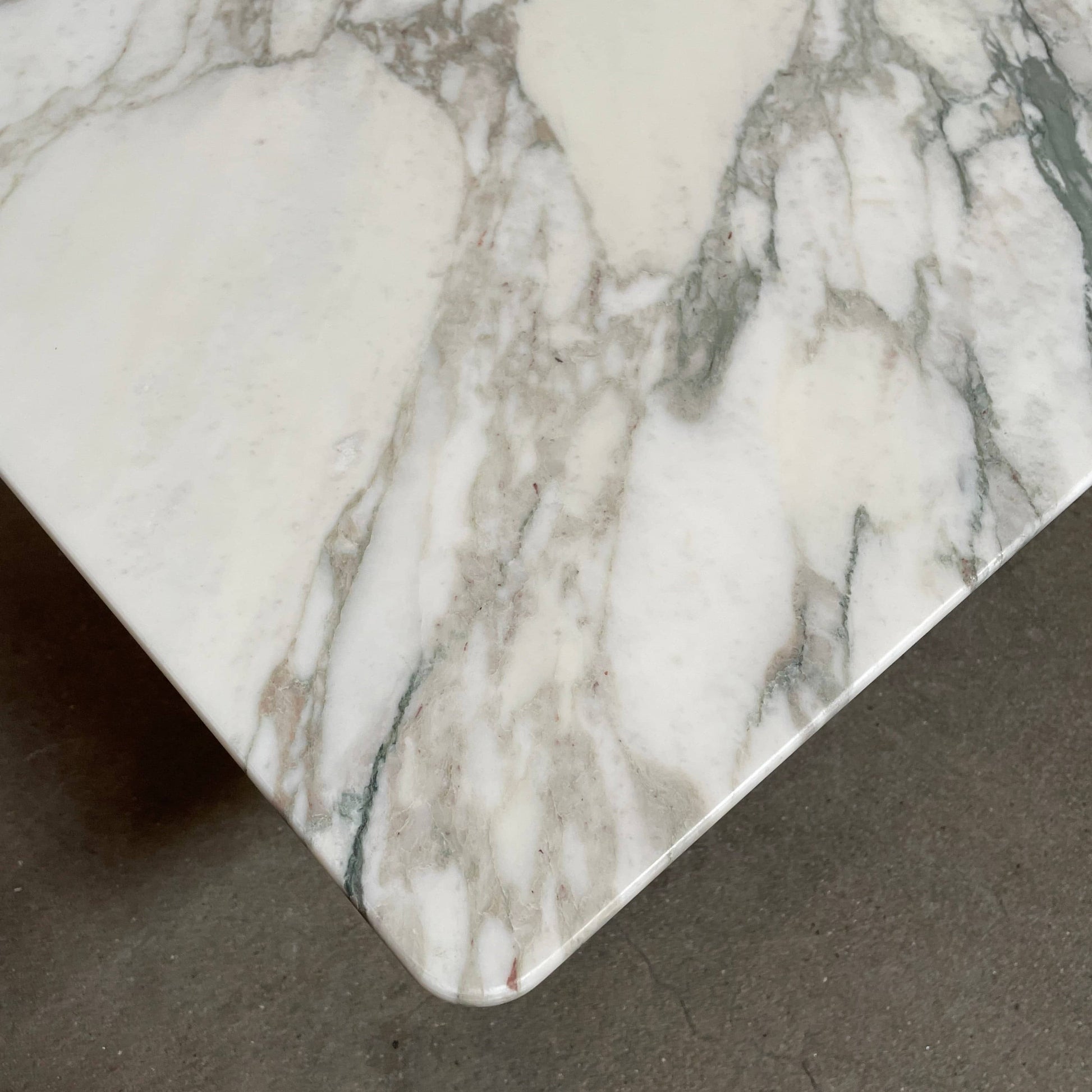 A Flexform Fly Marble Coffee Table with black legs on a white background.