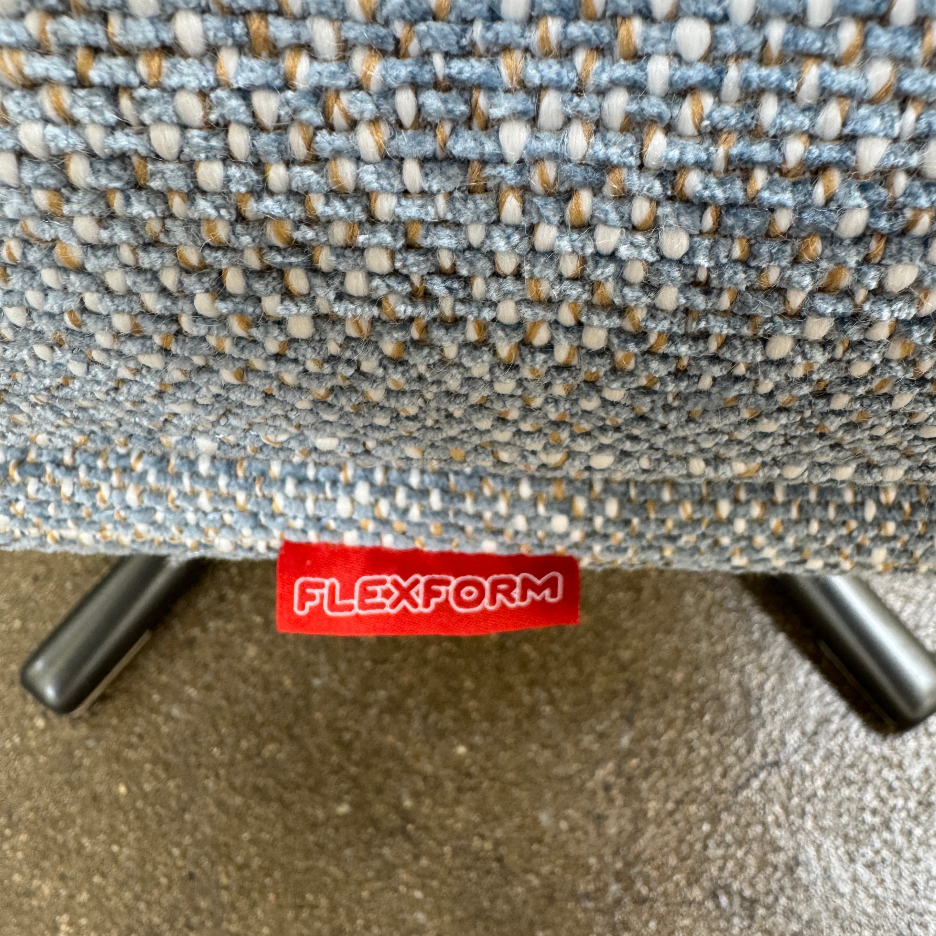 The Flexform Marlon Swivel Armchair and Ottoman, available with two covers, feature ergonomic design and black metal bases from Flexform, shown here in a modern gray finish against a plain white background.