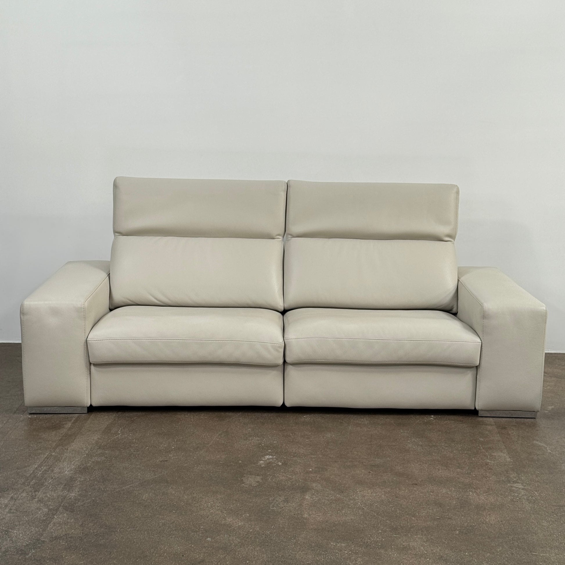 The Roche Bobois Leather Sofa With Movable Headrest features a modern beige design, wide armrests, metal legs, and an adjustable headrest—ideal for any contemporary living space.