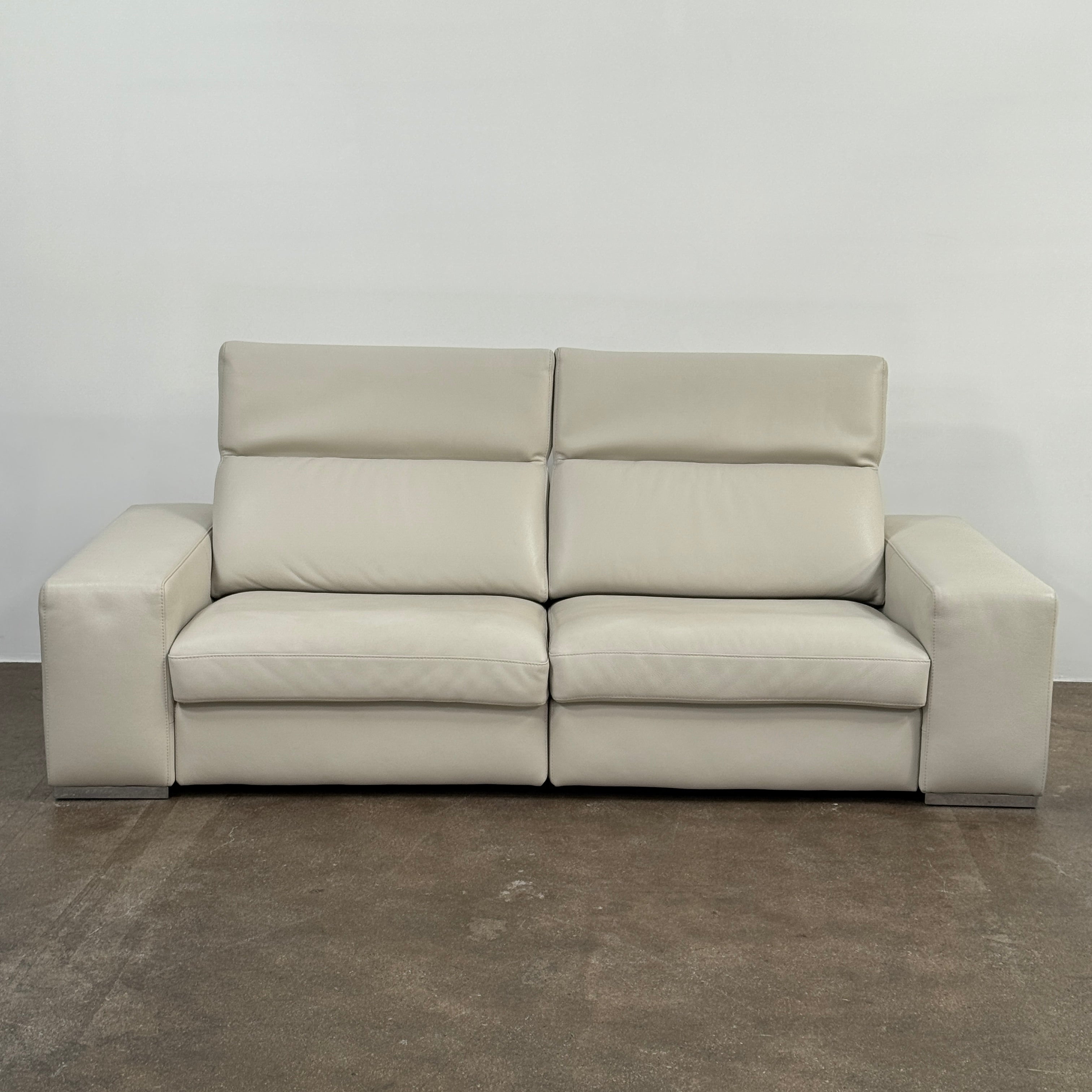 The Roche Bobois Leather Sofa With Movable Headrest features a modern beige design, wide armrests, metal legs, and an adjustable headrest—ideal for any contemporary living space.