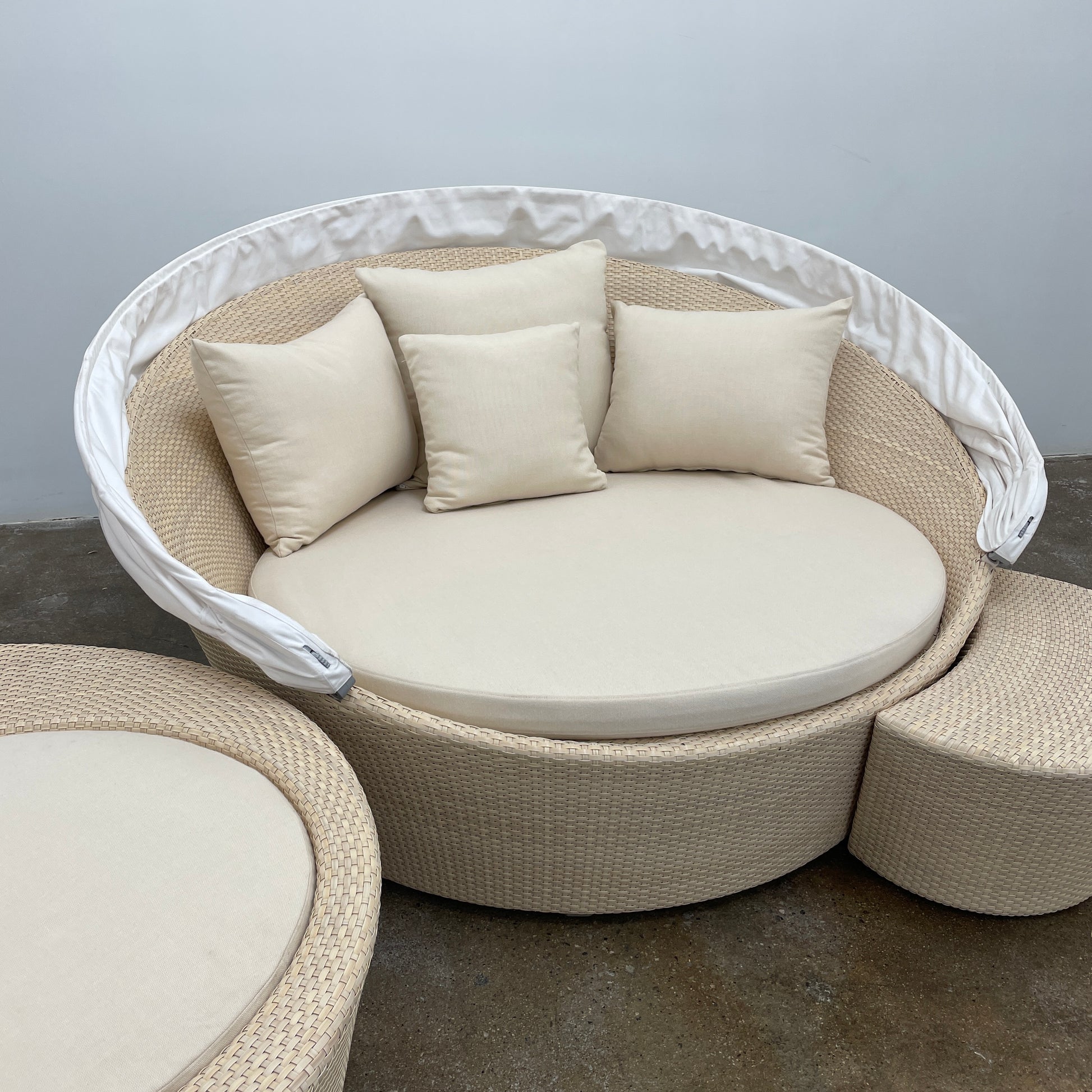 Experience the elegance of Richard Frinier Design with Dedon's Orbit Swivel Sofa Set, including a curved sofa with an adjustable canopy, ottoman, and side table. Cream-colored cushions add style and comfort to your outdoor ensemble.