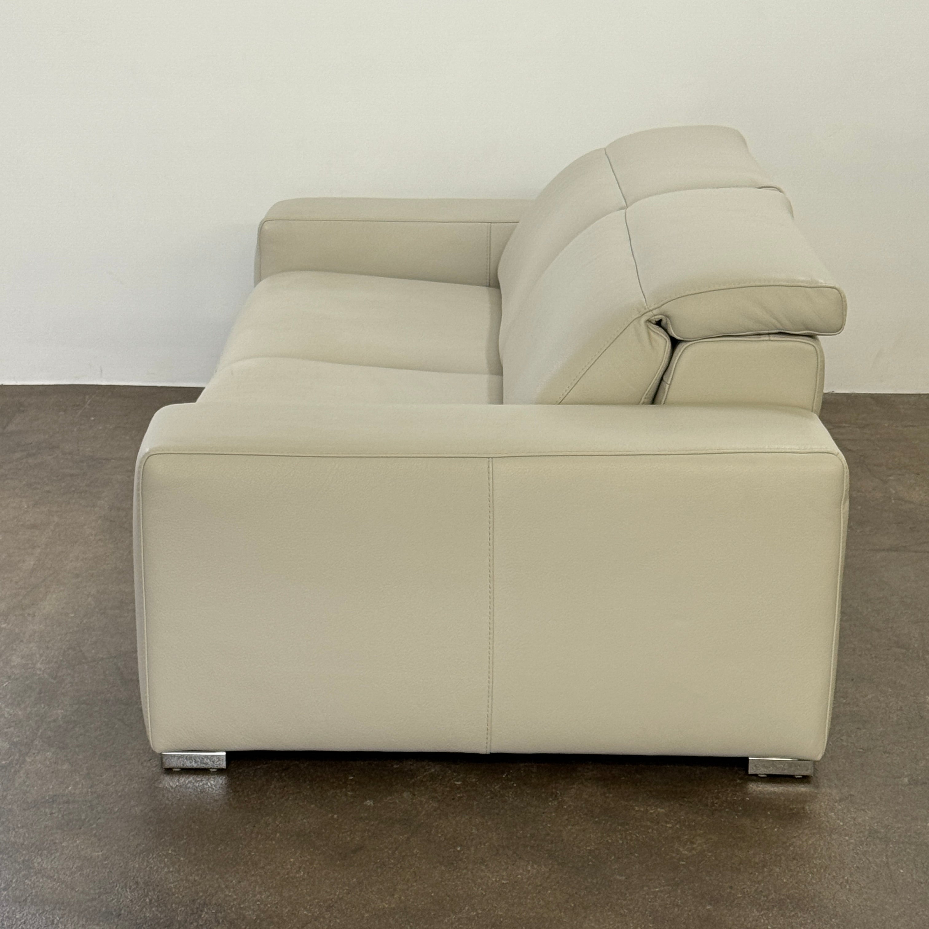 The Roche Bobois Leather Sofa With Movable Headrest features a modern beige design, wide armrests, metal legs, and an adjustable headrest—ideal for any contemporary living space.