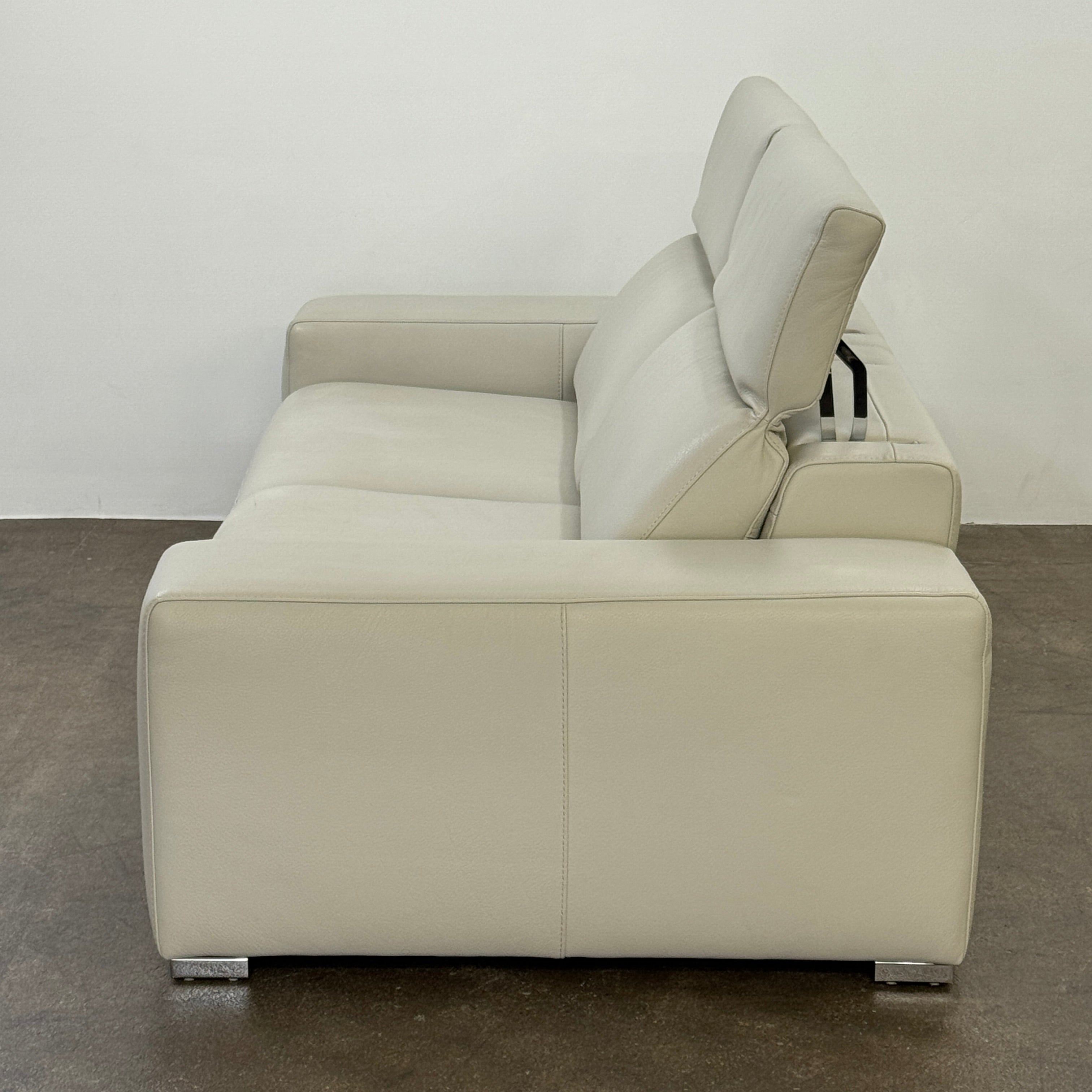 The Roche Bobois Leather Sofa With Movable Headrest features a modern beige design, wide armrests, metal legs, and an adjustable headrest—ideal for any contemporary living space.