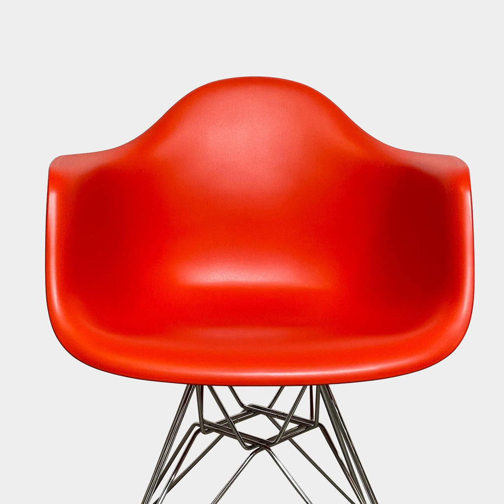 A red Eames Molded Plastic Shell Armchair, providing comfort, placed on a white background.