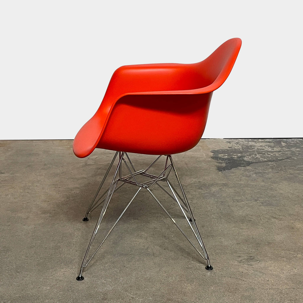 A red Eames Molded Plastic Shell Armchair, providing comfort, placed on a white background.
