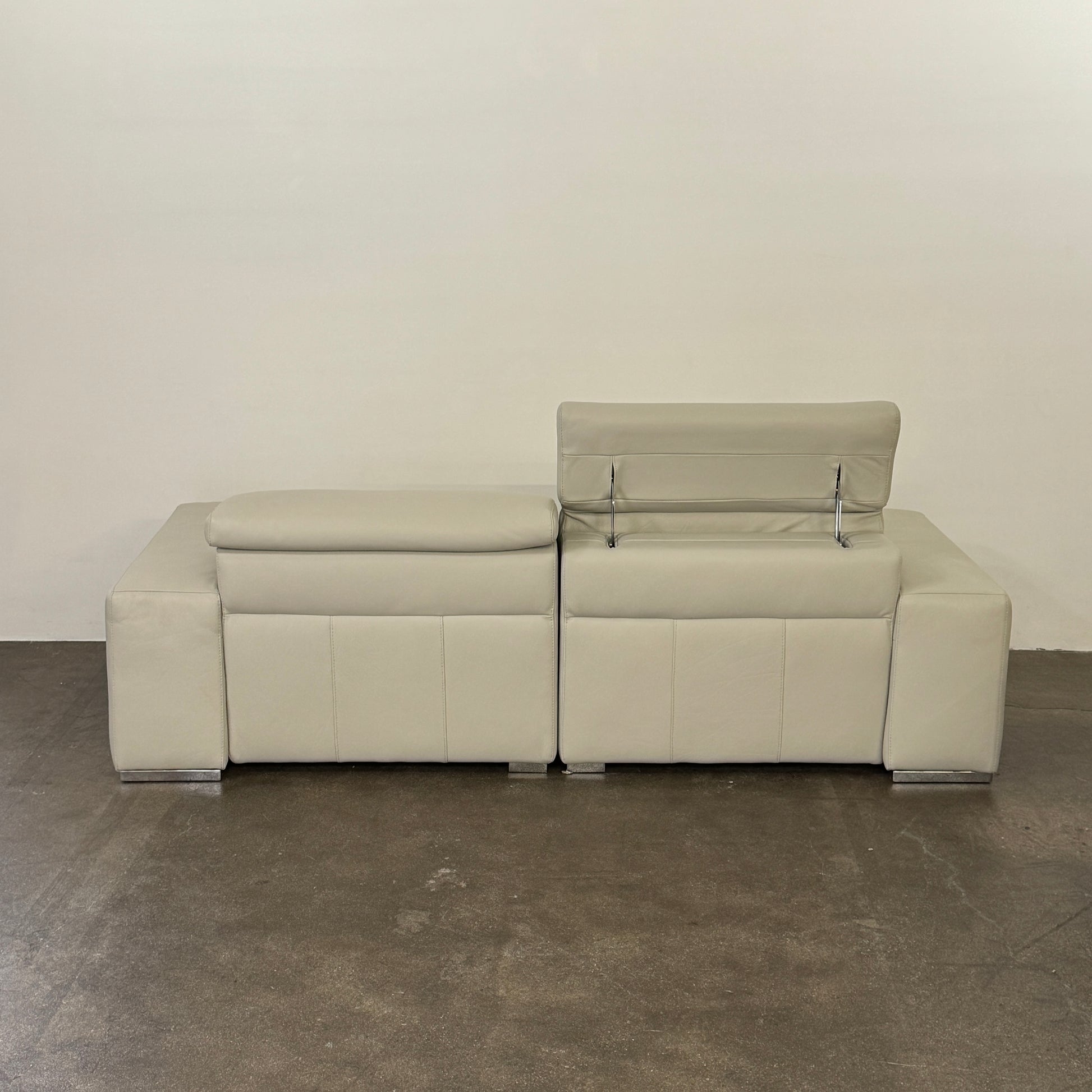 The Roche Bobois Leather Sofa With Movable Headrest features a modern beige design, wide armrests, metal legs, and an adjustable headrest—ideal for any contemporary living space.