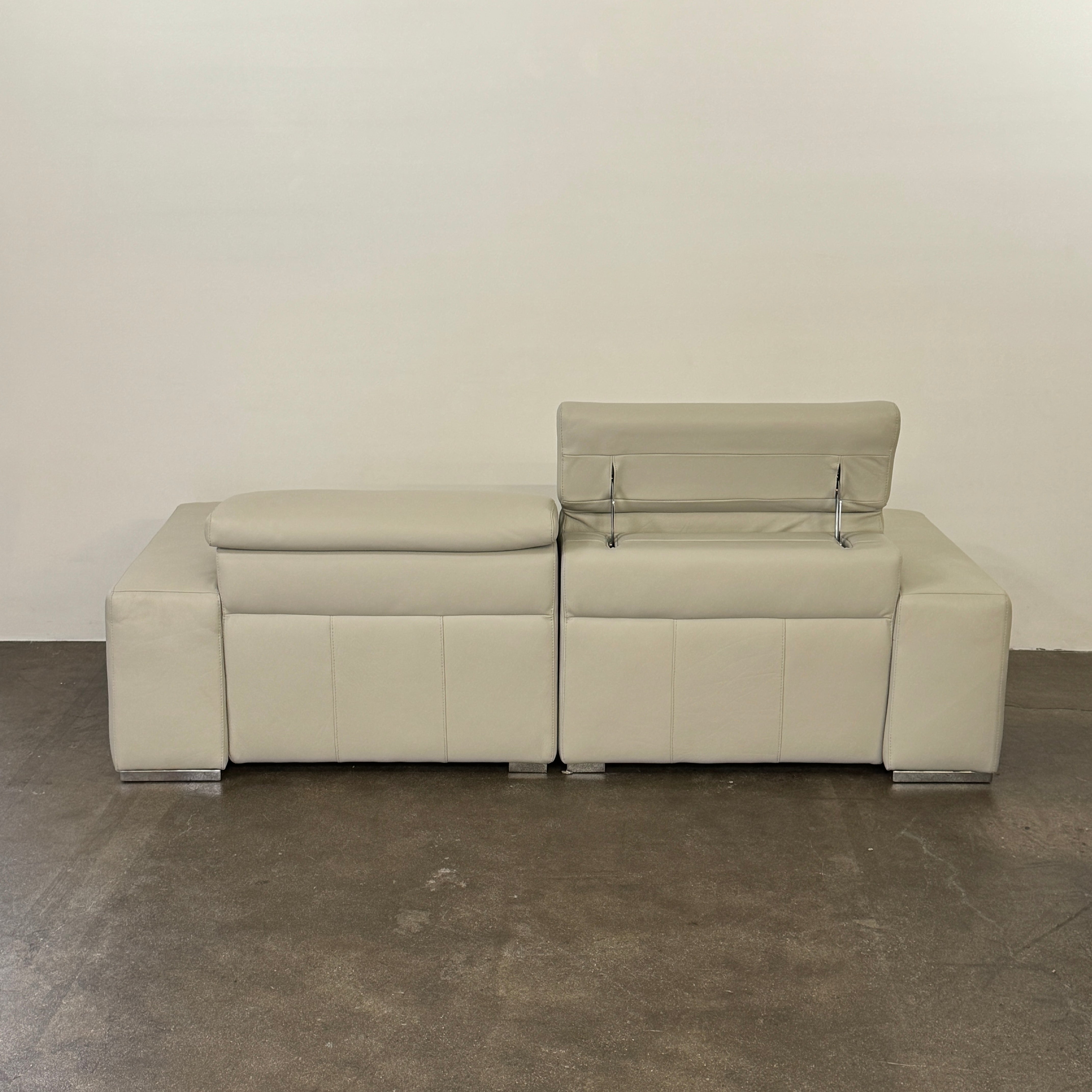 The Roche Bobois Leather Sofa With Movable Headrest features a modern beige design, wide armrests, metal legs, and an adjustable headrest—ideal for any contemporary living space.