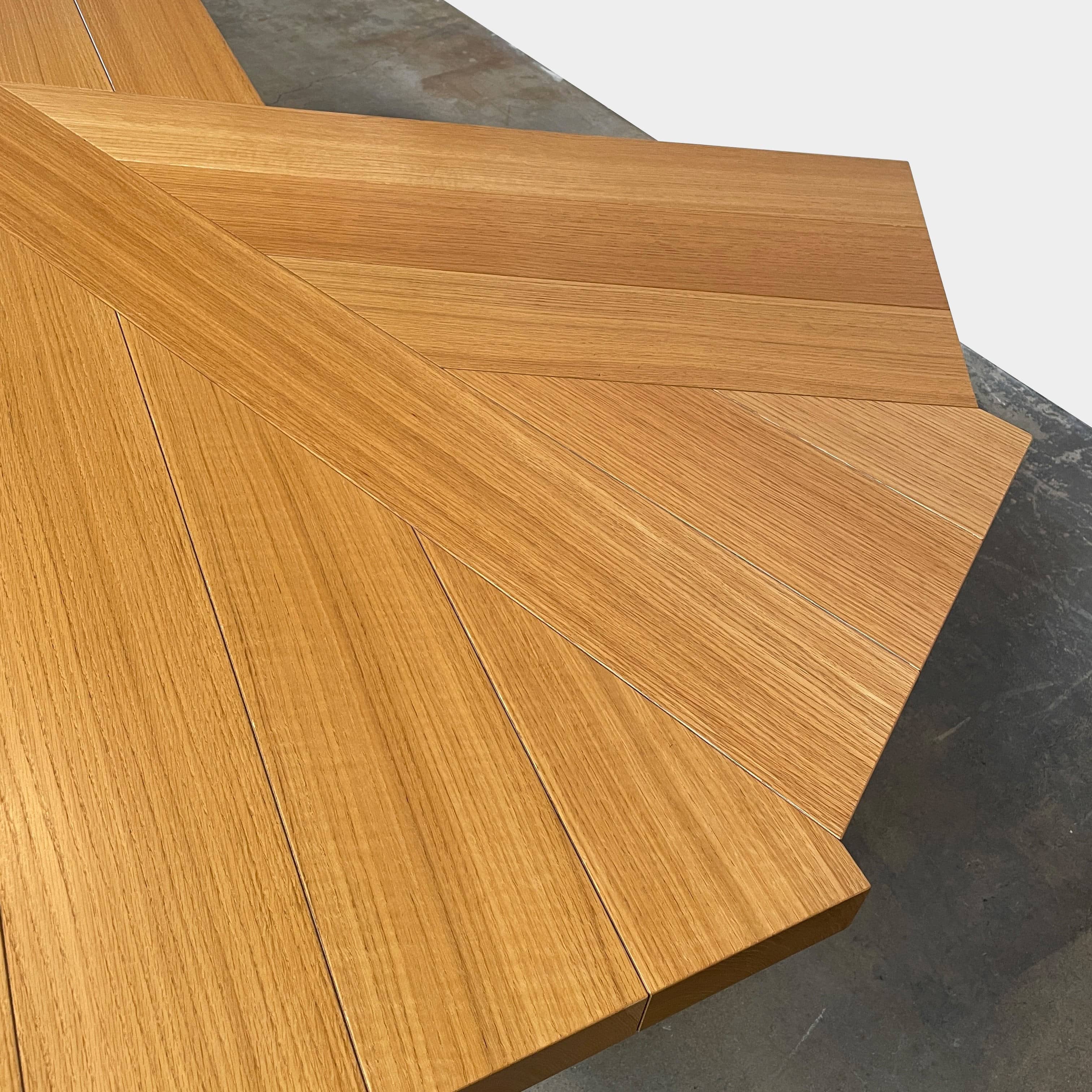 Modern Cassina Ventaglio Table inspired by Charlotte Perriand's functional ingenuity, with an asymmetrical, angular top and four cylindrical legs, isolated on a white background.