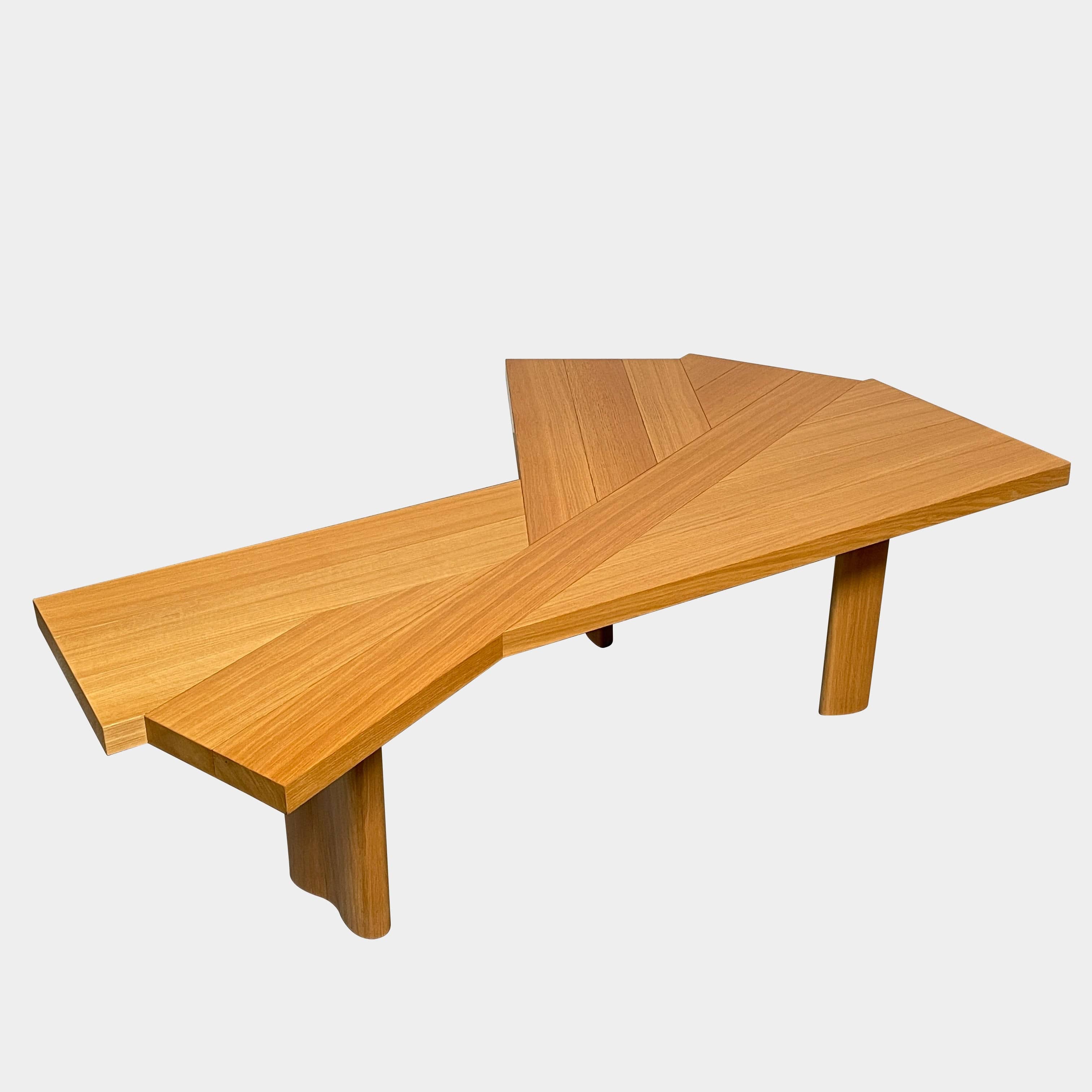 Modern Cassina Ventaglio Table inspired by Charlotte Perriand's functional ingenuity, with an asymmetrical, angular top and four cylindrical legs, isolated on a white background.