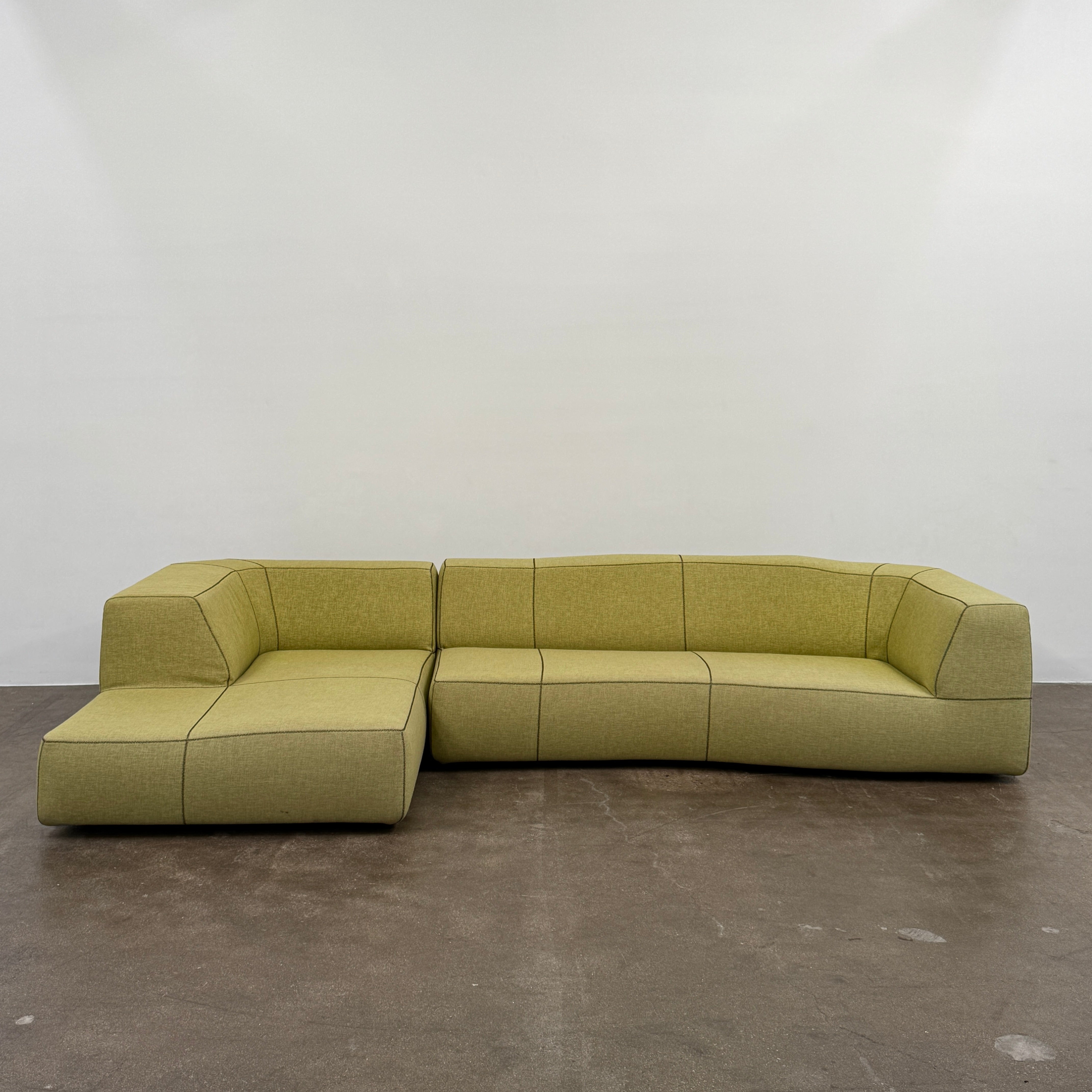 The B&B Italia Bend Sectional Sofa by B&B Italia features olive green fabric, black accent stitching, low backrests, and a geometric design inspired by Patricia Urquiola, shown on a plain white background.