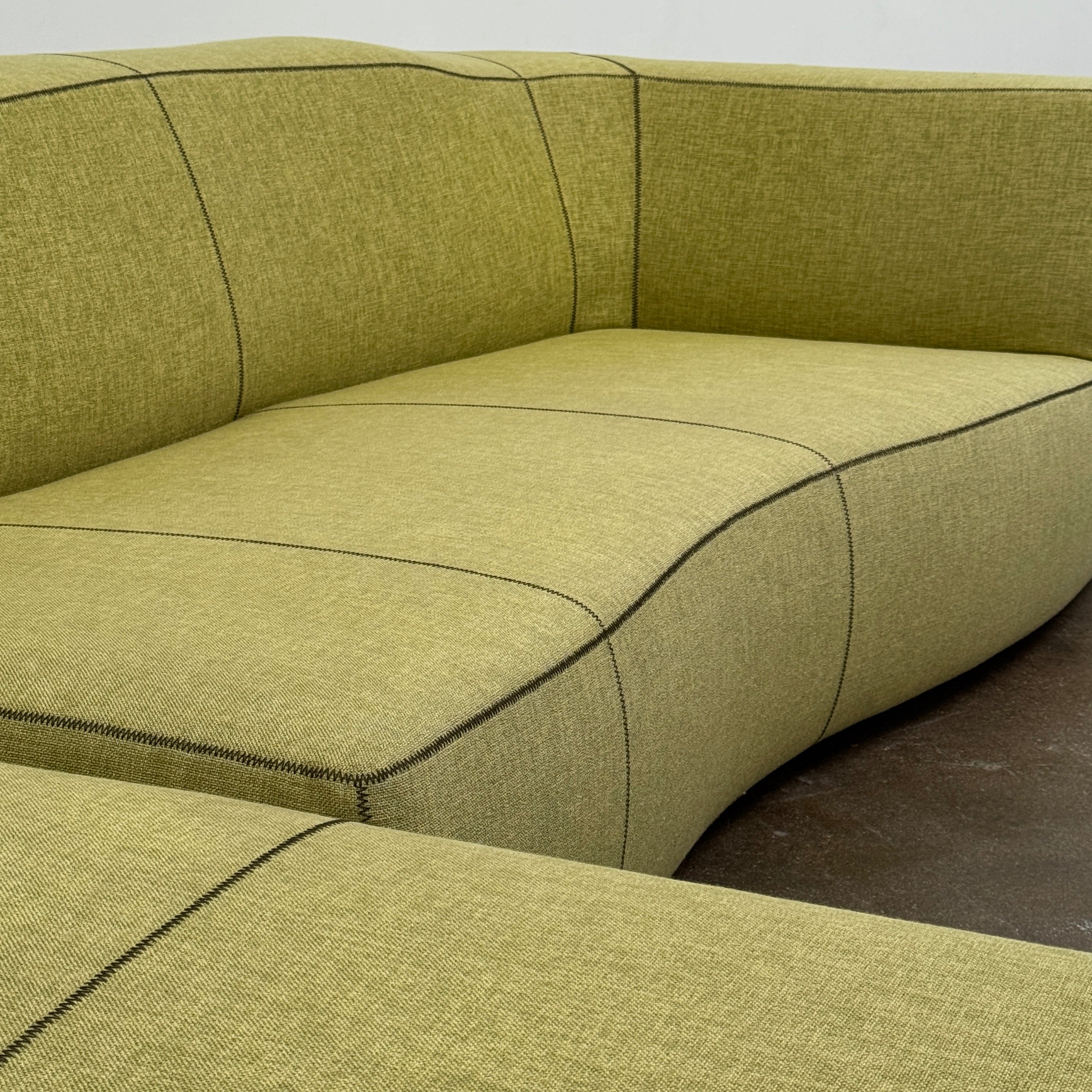 The B&B Italia Bend Sectional Sofa by B&B Italia features olive green fabric, black accent stitching, low backrests, and a geometric design inspired by Patricia Urquiola, shown on a plain white background.