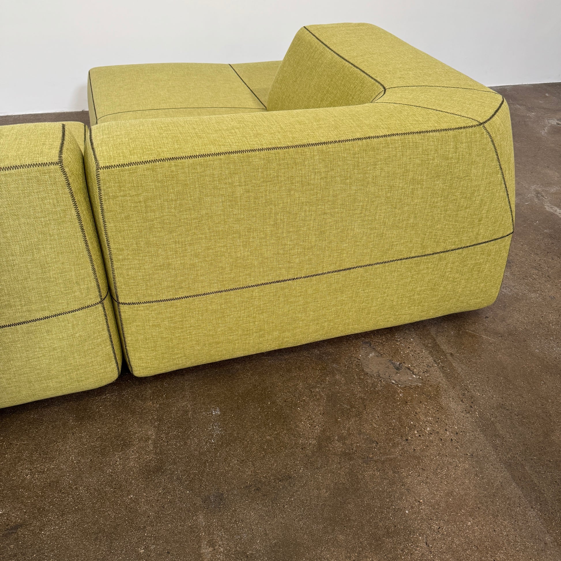 The B&B Italia Bend Sectional Sofa by B&B Italia features olive green fabric, black accent stitching, low backrests, and a geometric design inspired by Patricia Urquiola, shown on a plain white background.