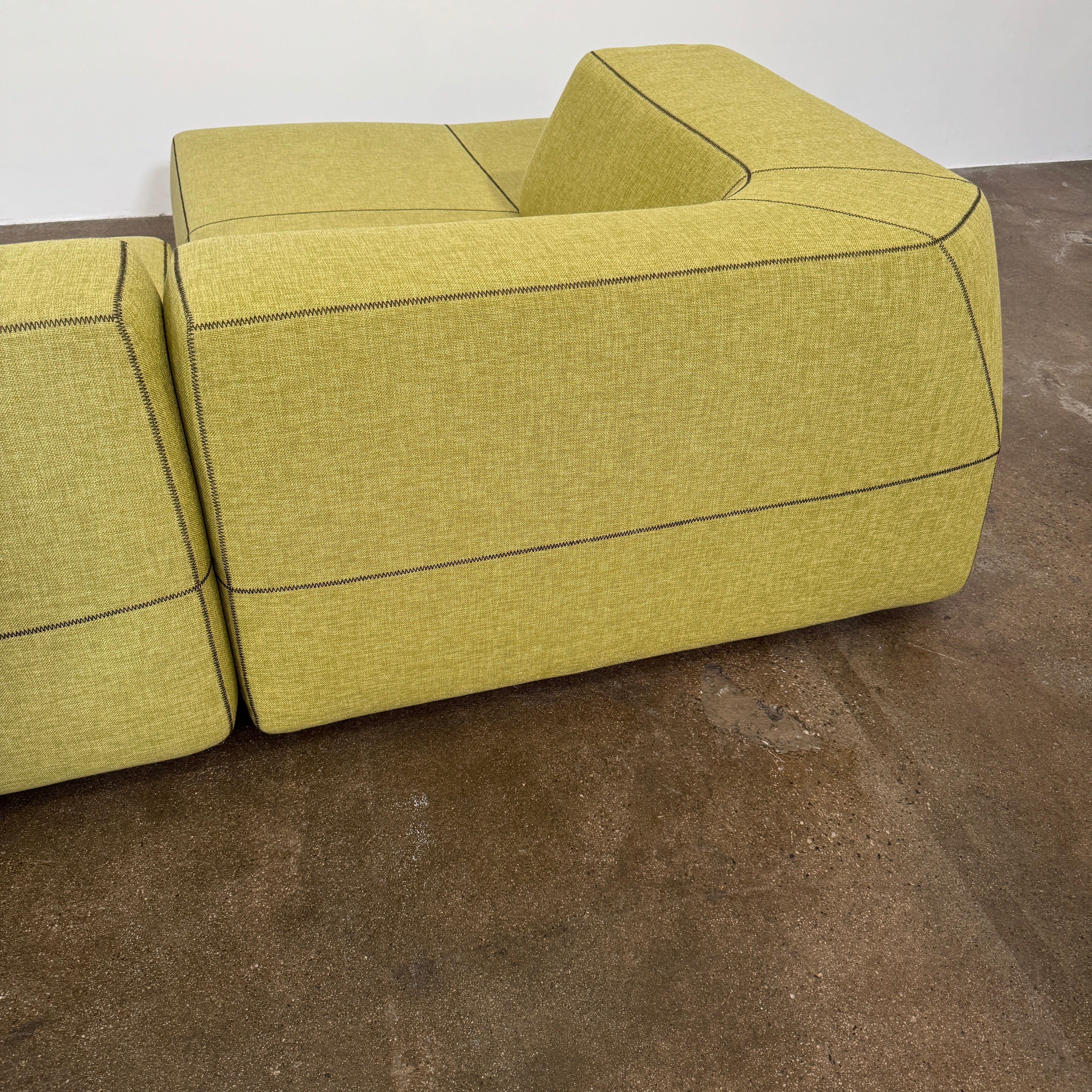 The B&B Italia Bend Sectional Sofa by B&B Italia features olive green fabric, black accent stitching, low backrests, and a geometric design inspired by Patricia Urquiola, shown on a plain white background.