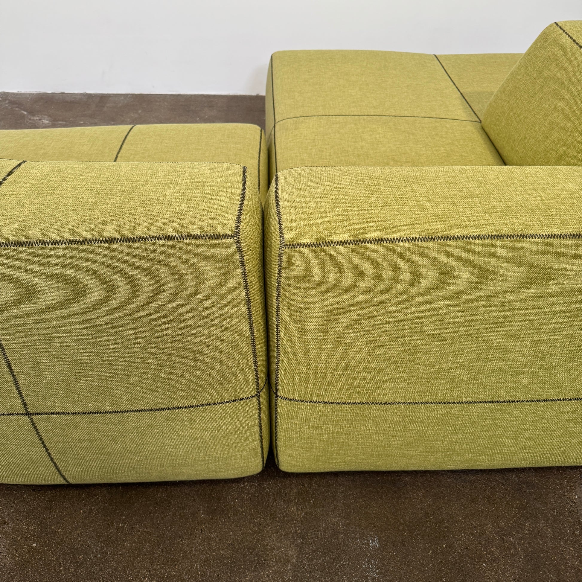 The B&B Italia Bend Sectional Sofa by B&B Italia features olive green fabric, black accent stitching, low backrests, and a geometric design inspired by Patricia Urquiola, shown on a plain white background.