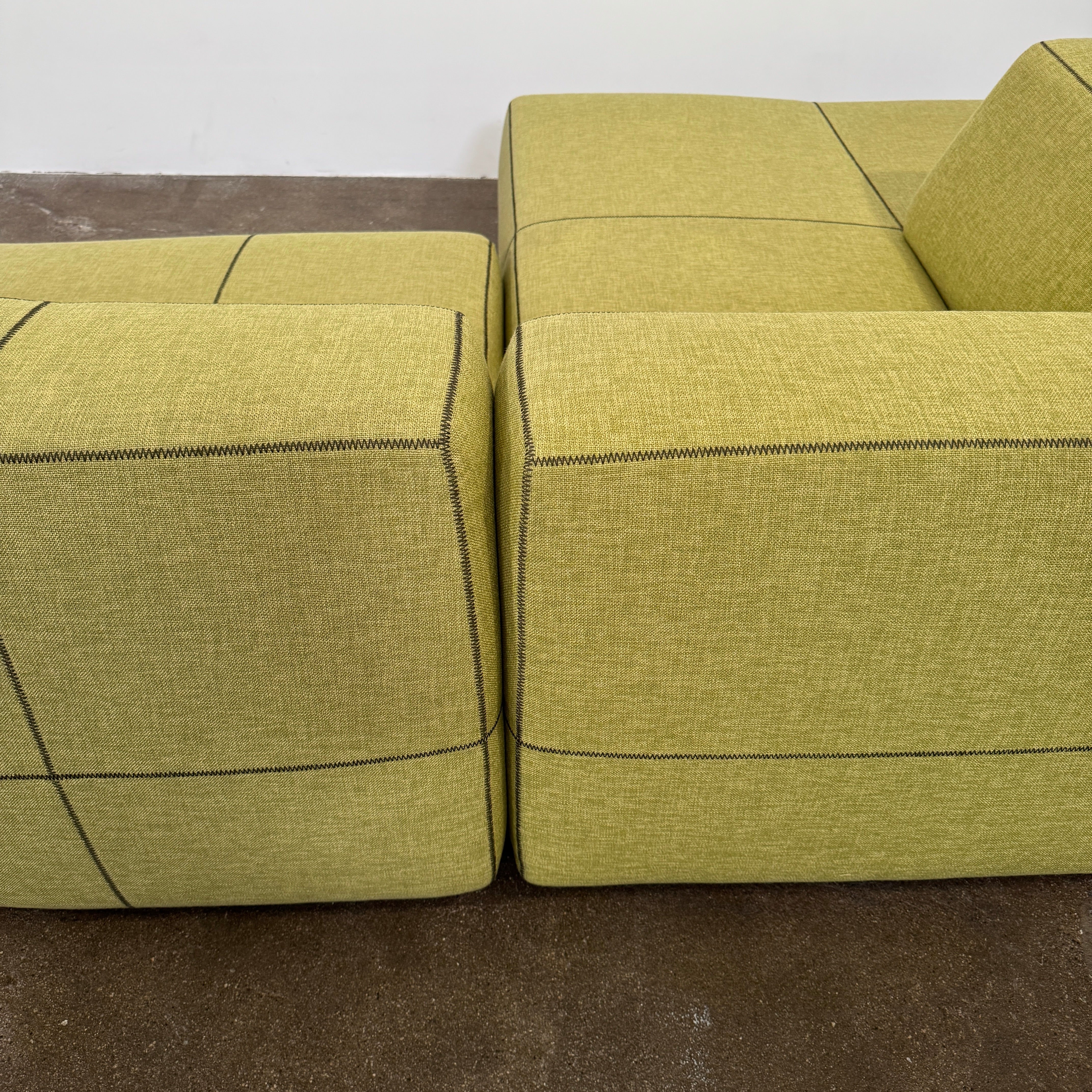 The B&B Italia Bend Sectional Sofa by B&B Italia features olive green fabric, black accent stitching, low backrests, and a geometric design inspired by Patricia Urquiola, shown on a plain white background.