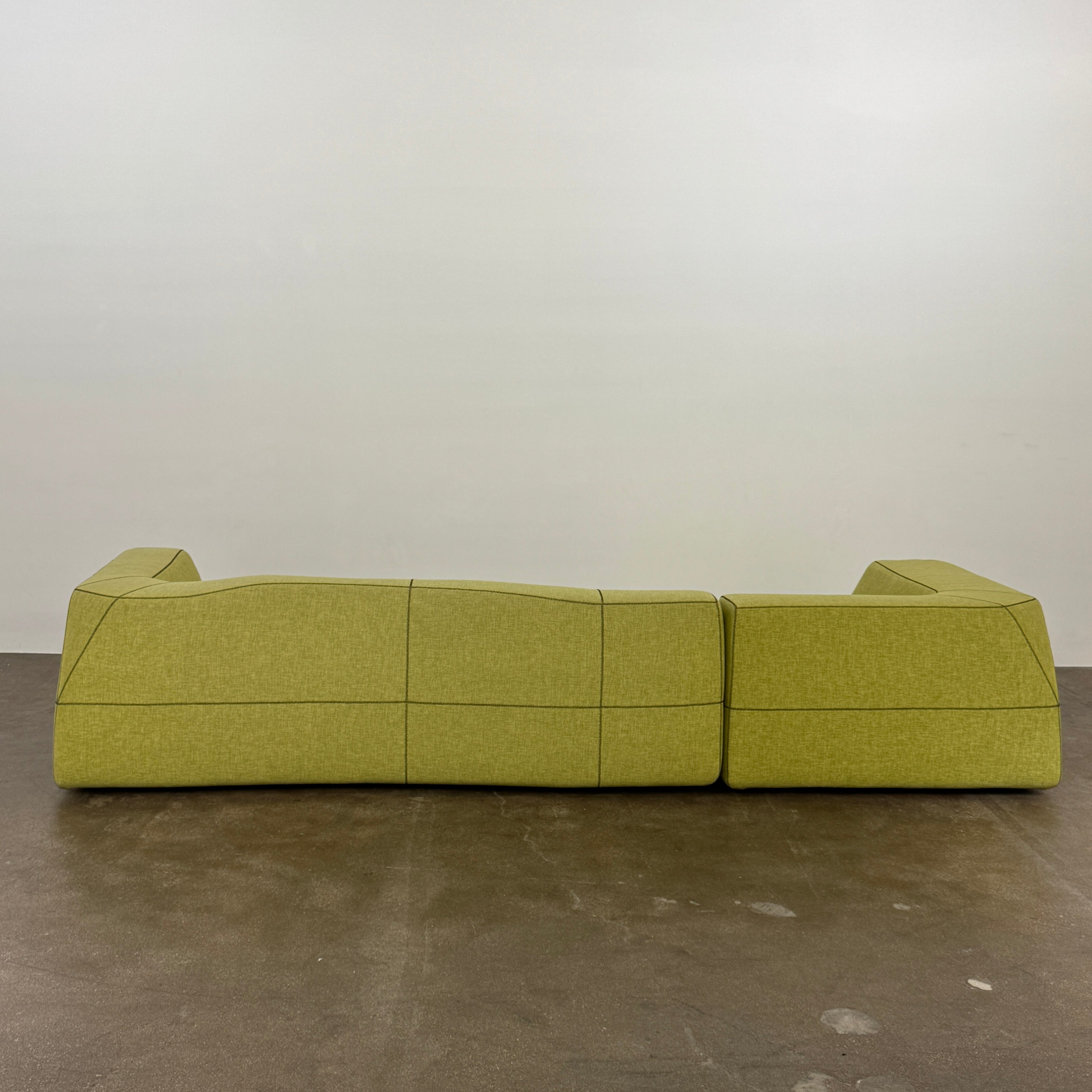 The B&B Italia Bend Sectional Sofa by B&B Italia features olive green fabric, black accent stitching, low backrests, and a geometric design inspired by Patricia Urquiola, shown on a plain white background.