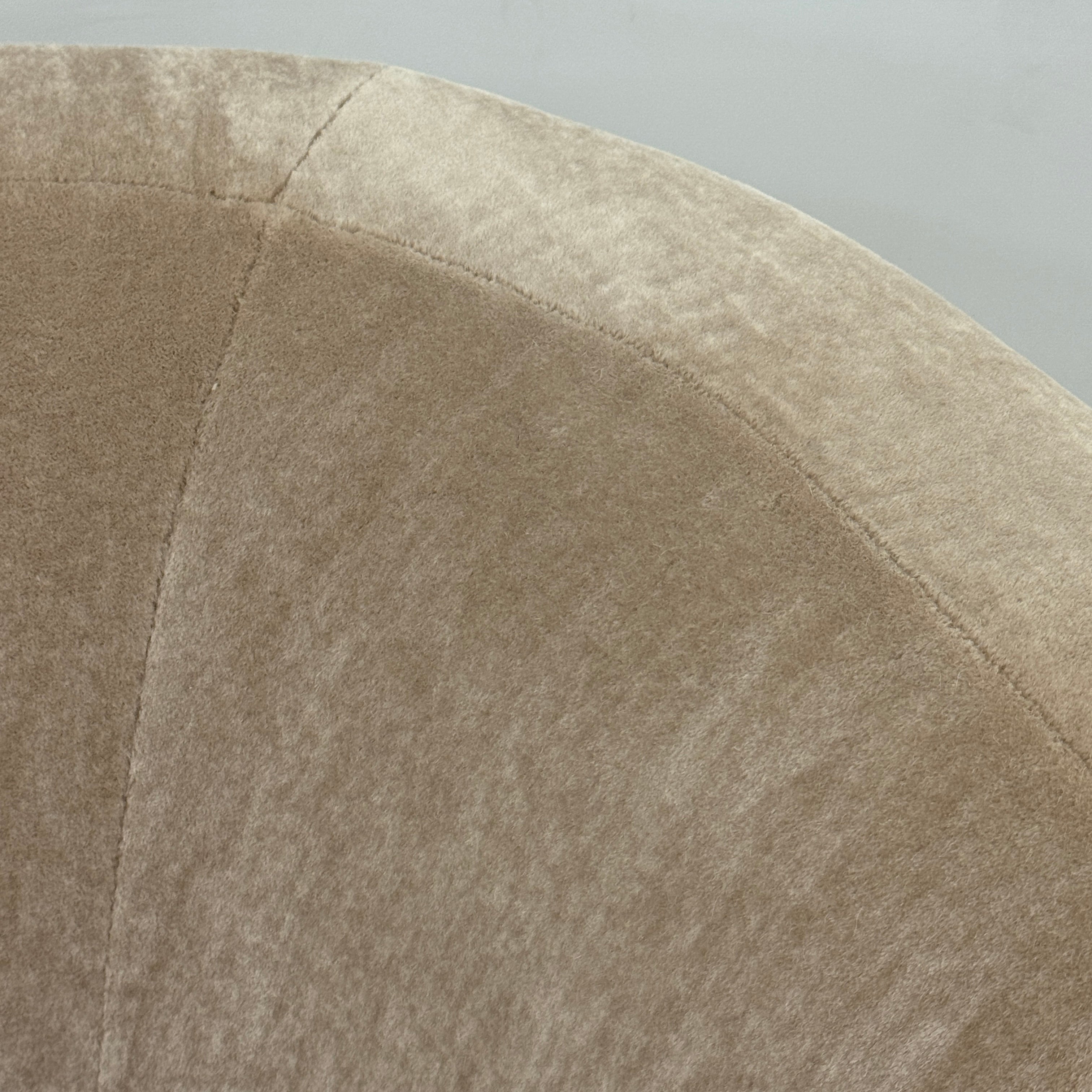 The tan, modern Holly Hunt Caste Malta Sofa with rounded edges sits stylishly on a polished concrete floor against a white wall, showcasing minimalist design inspired by Holly Hunt’s signature aesthetic.