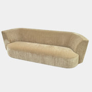 The tan, modern Holly Hunt Caste Malta Sofa with rounded edges sits stylishly on a polished concrete floor against a white wall, showcasing minimalist design inspired by Holly Hunt’s signature aesthetic.