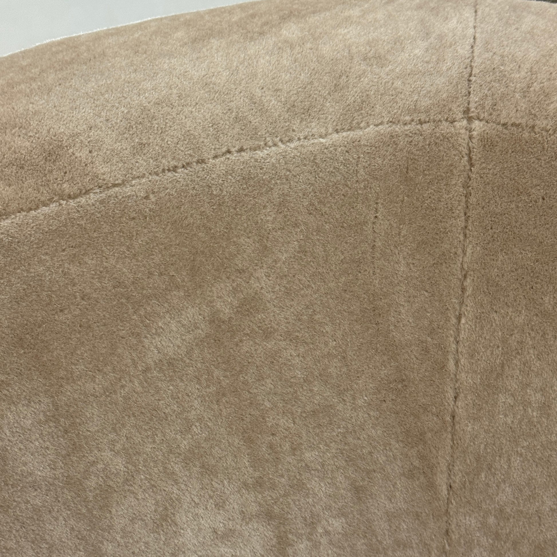 The tan, modern Holly Hunt Caste Malta Sofa with rounded edges sits stylishly on a polished concrete floor against a white wall, showcasing minimalist design inspired by Holly Hunt’s signature aesthetic.