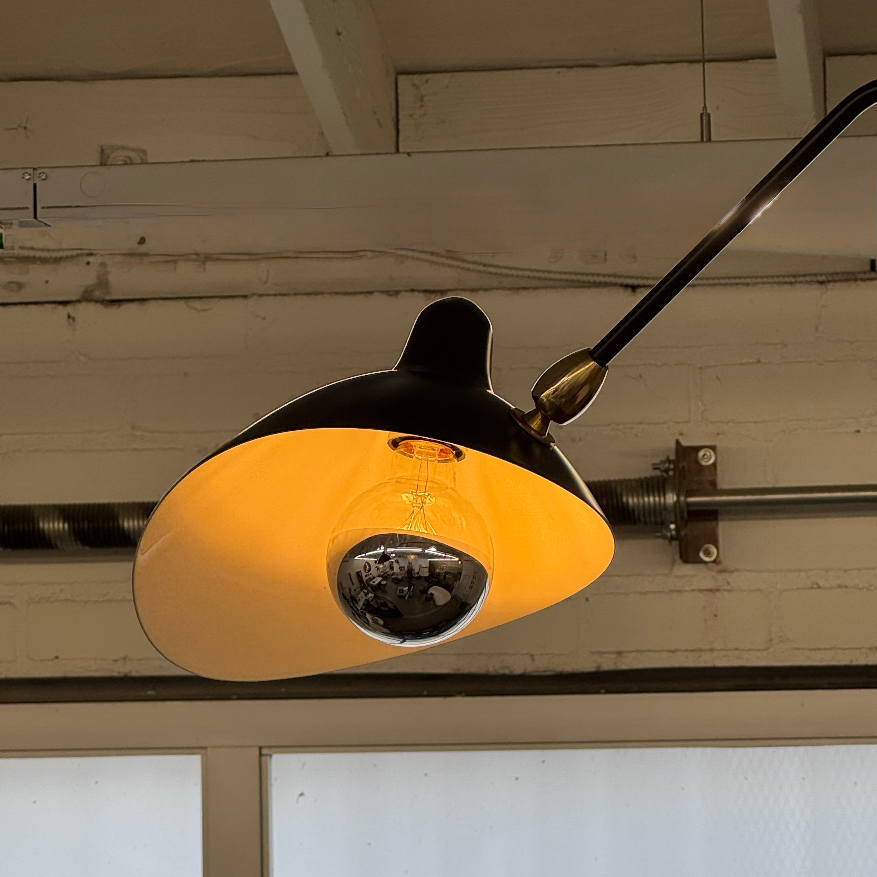 The Serge Mouille 3 Arm Ceiling Light by Serge Mouille features three black conical shades on adjustable metal arms from a central ceiling mount, displayed against a plain white background.