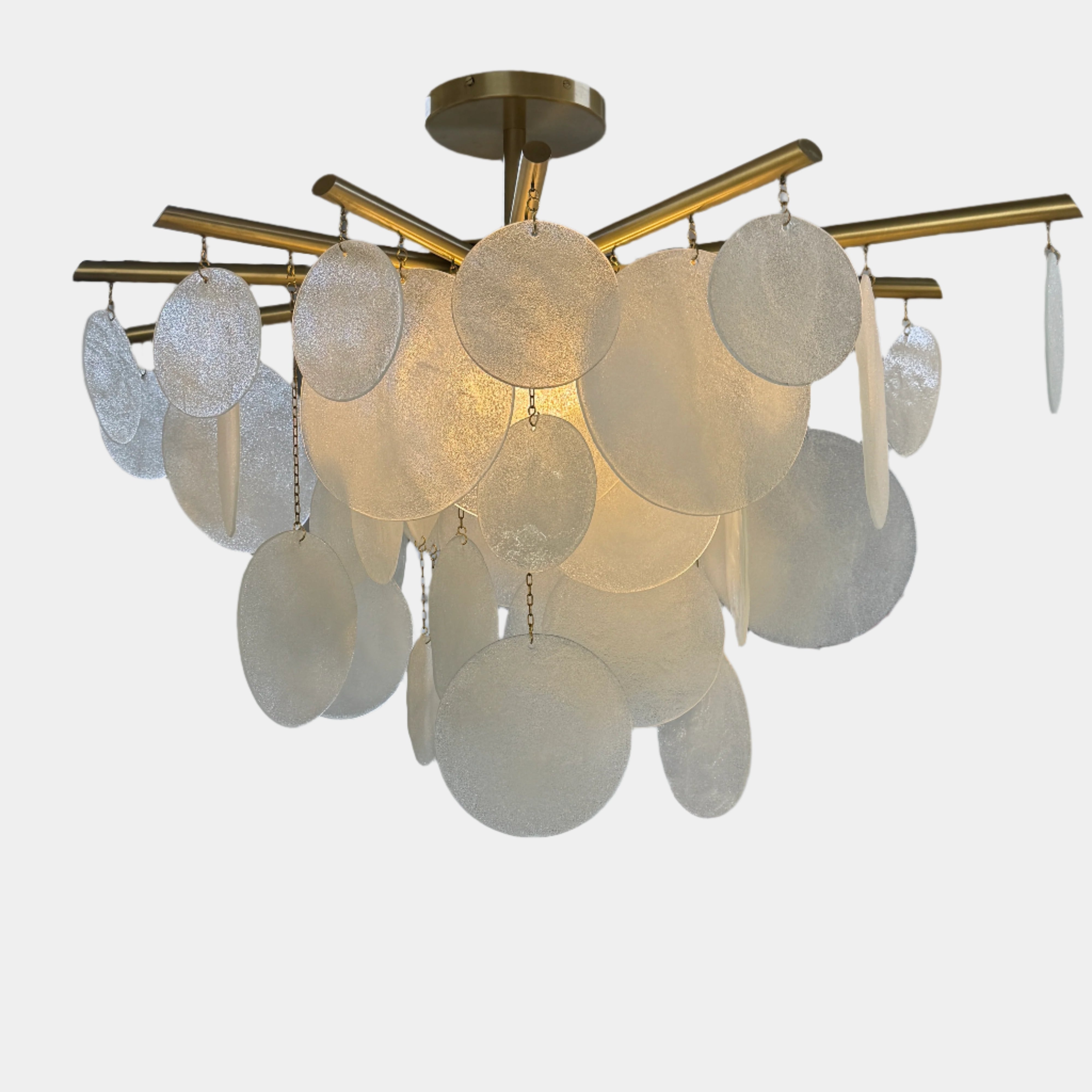 The Nimbu Medium Chandelier by Nimbu features a brass finish and layered frosted glass discs, creating a soft, warm glow—ideal as a contemporary centerpiece.