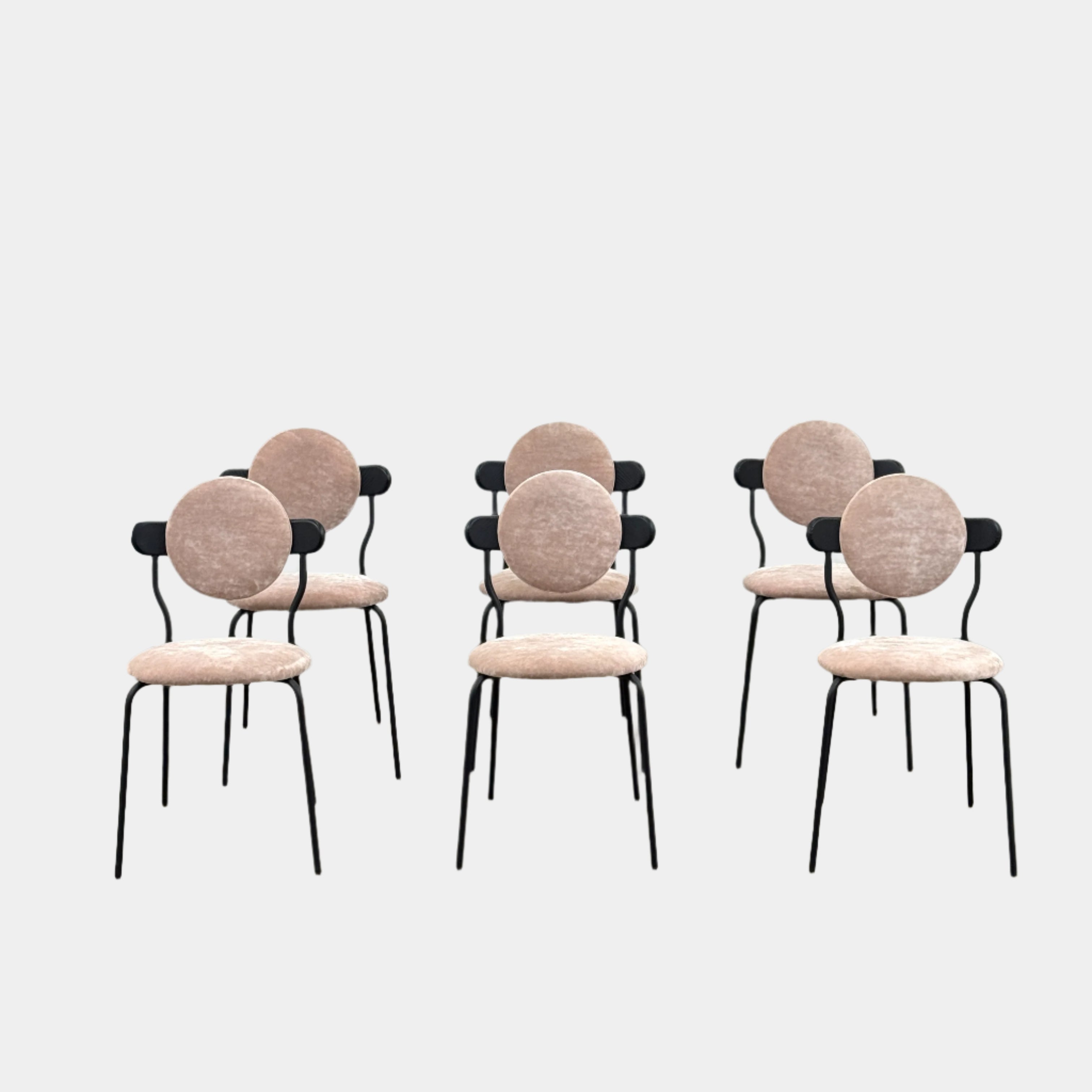 Six Modern Resale La Chance Planet Dining Chairs, set of 6, feature round light pink velvet seats and black metal legs, arranged in two rows on a bare concrete floor against a white wall—perfect for adding modern elegance.