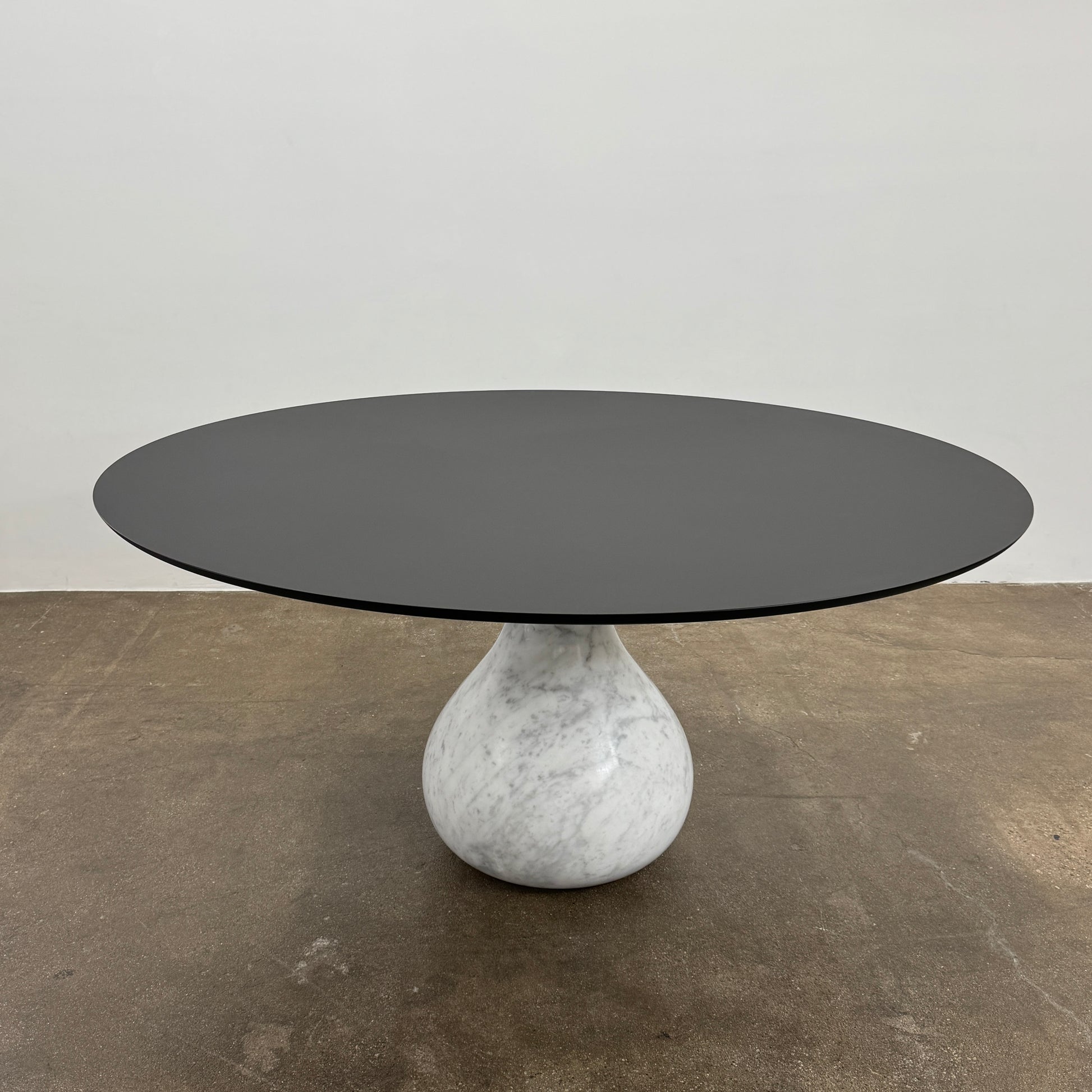 The Roche Bobois Aqua Round Table features a sleek black top and a teardrop-shaped white marble base, blending elegance and modern style—an iconic design by Roche Bobois, shown here against a plain white background.