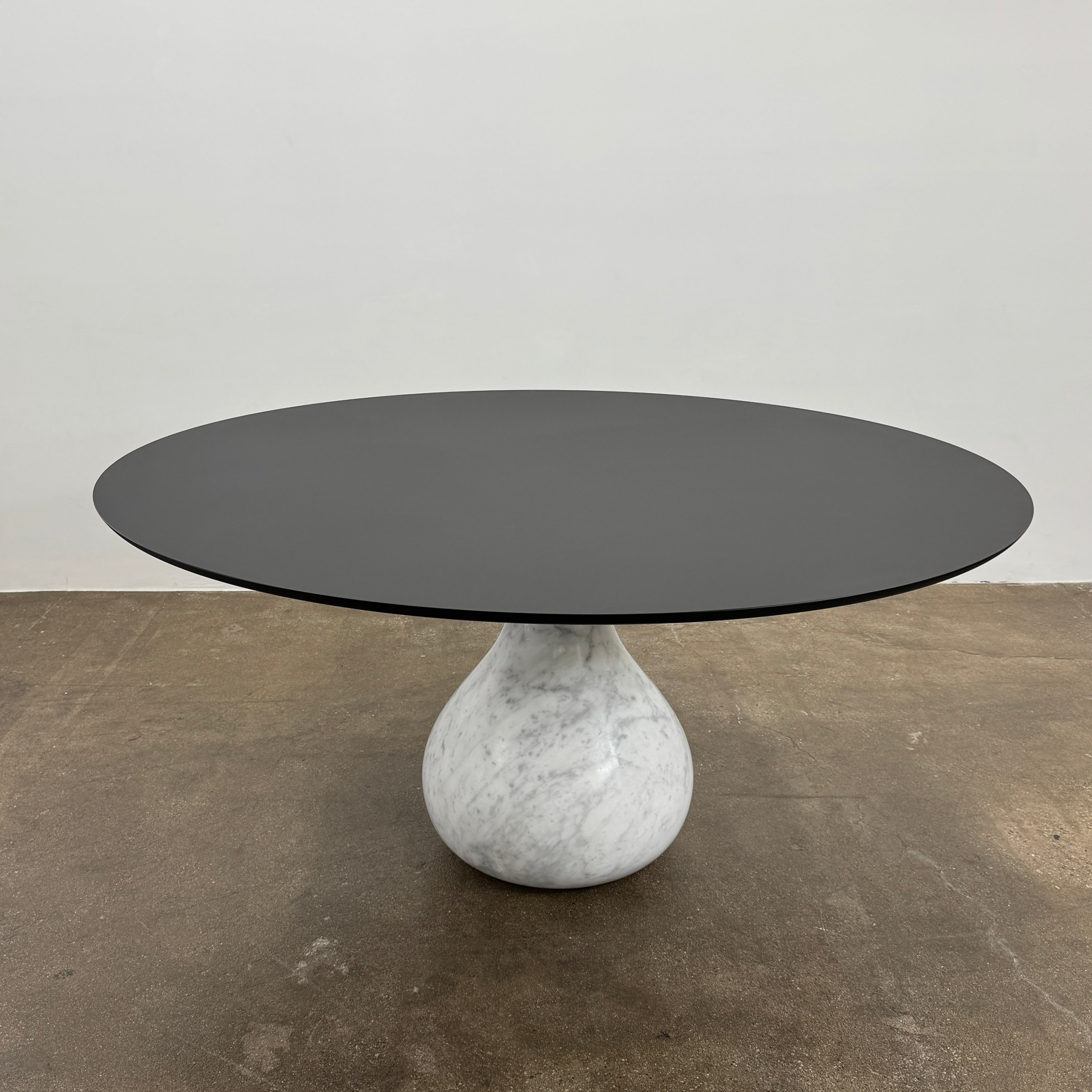 The Roche Bobois Aqua Round Table features a sleek black top and a teardrop-shaped white marble base, blending elegance and modern style—an iconic design by Roche Bobois, shown here against a plain white background.