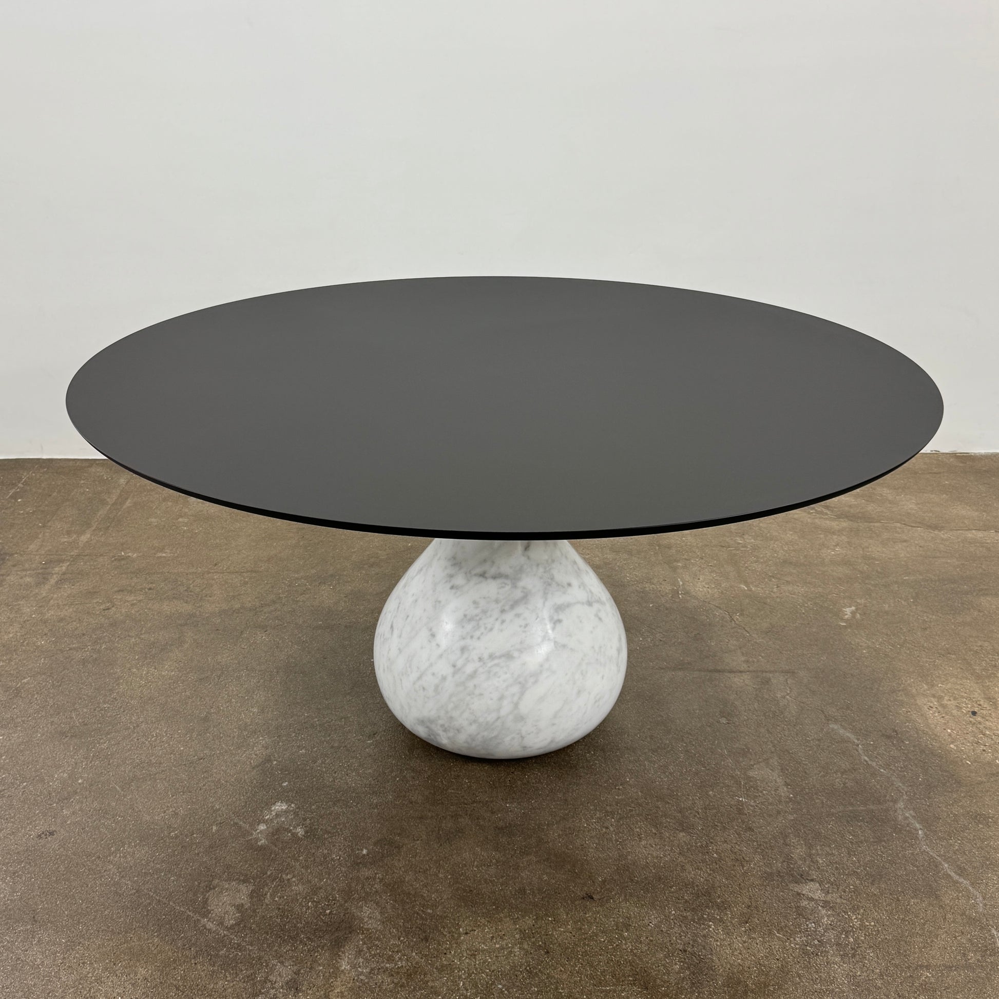 The Roche Bobois Aqua Round Table features a sleek black top and a teardrop-shaped white marble base, blending elegance and modern style—an iconic design by Roche Bobois, shown here against a plain white background.