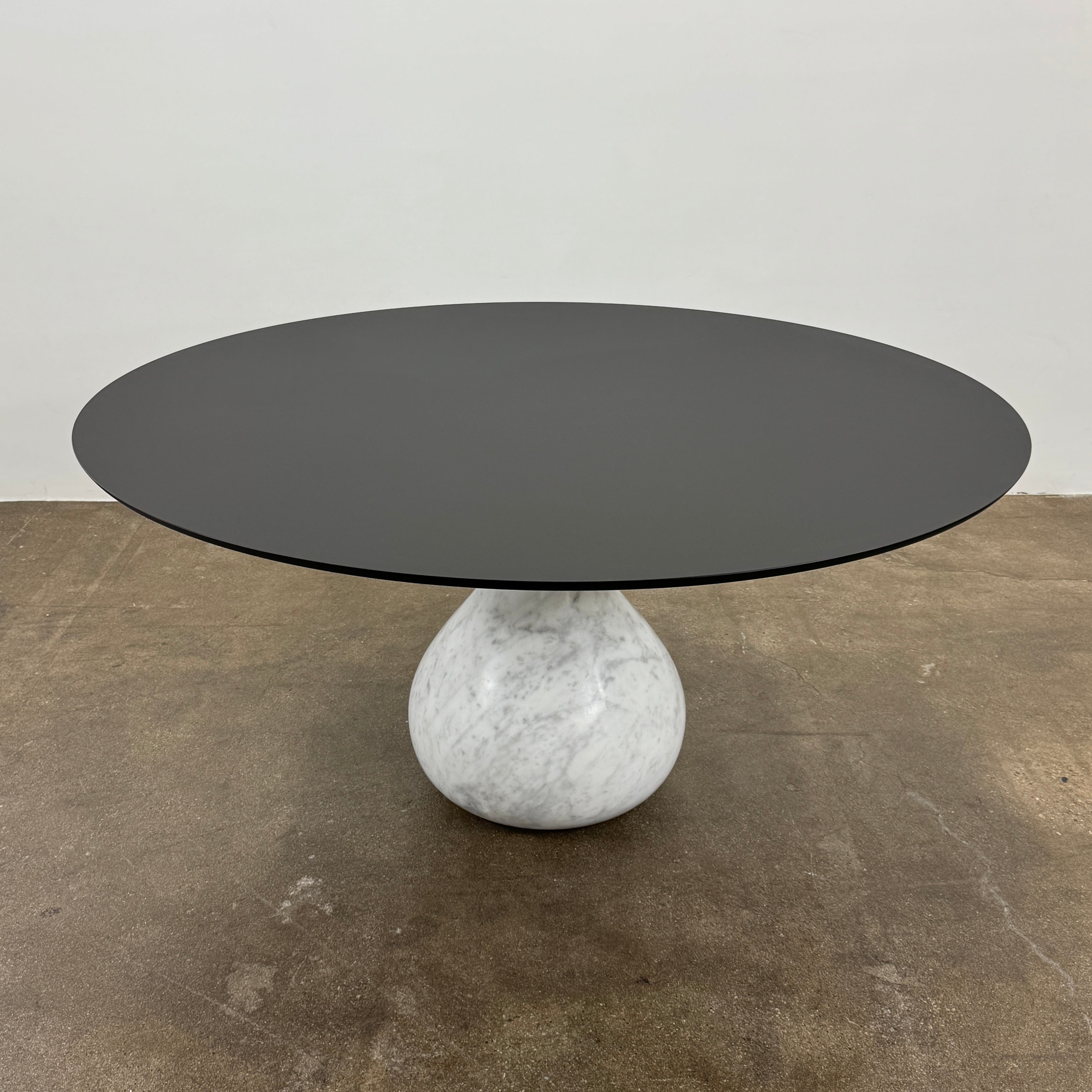 The Roche Bobois Aqua Round Table features a sleek black top and a teardrop-shaped white marble base, blending elegance and modern style—an iconic design by Roche Bobois, shown here against a plain white background.