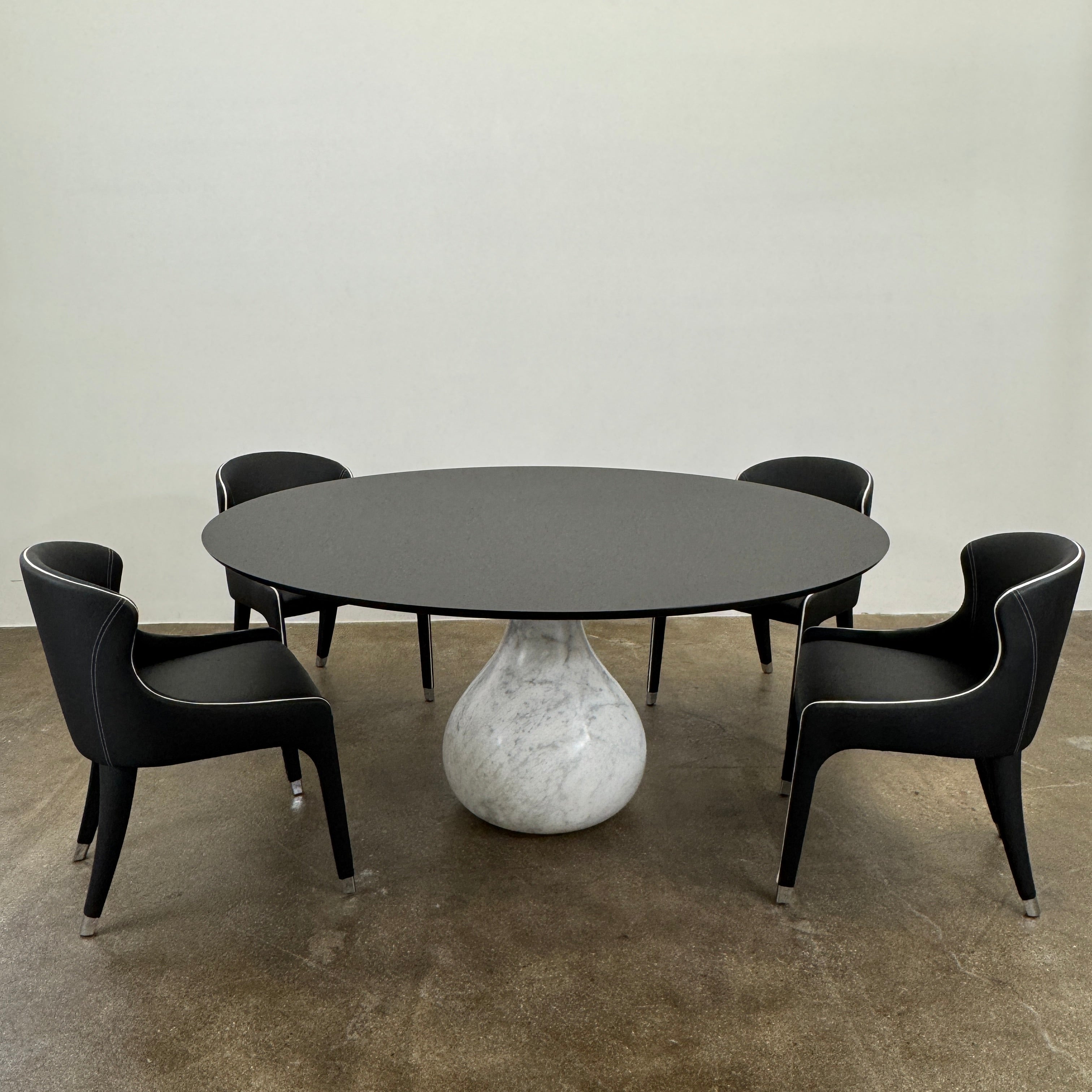 The Roche Bobois Aqua Round Table features a sleek black top and a teardrop-shaped white marble base, blending elegance and modern style—an iconic design by Roche Bobois, shown here against a plain white background.