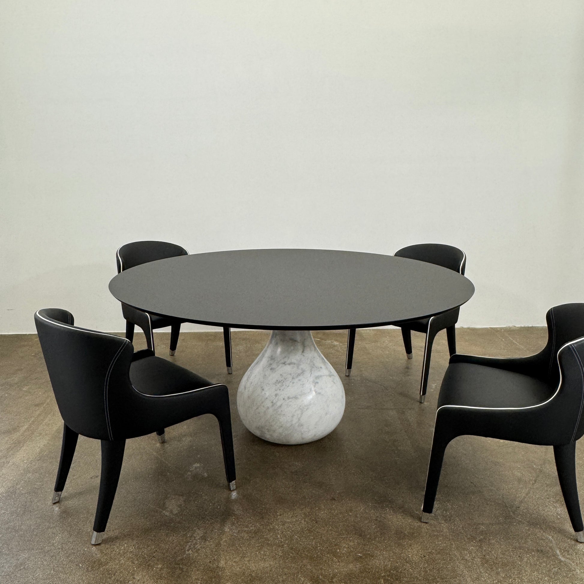 The Roche Bobois Aqua Round Table features a sleek black top and a teardrop-shaped white marble base, blending elegance and modern style—an iconic design by Roche Bobois, shown here against a plain white background.