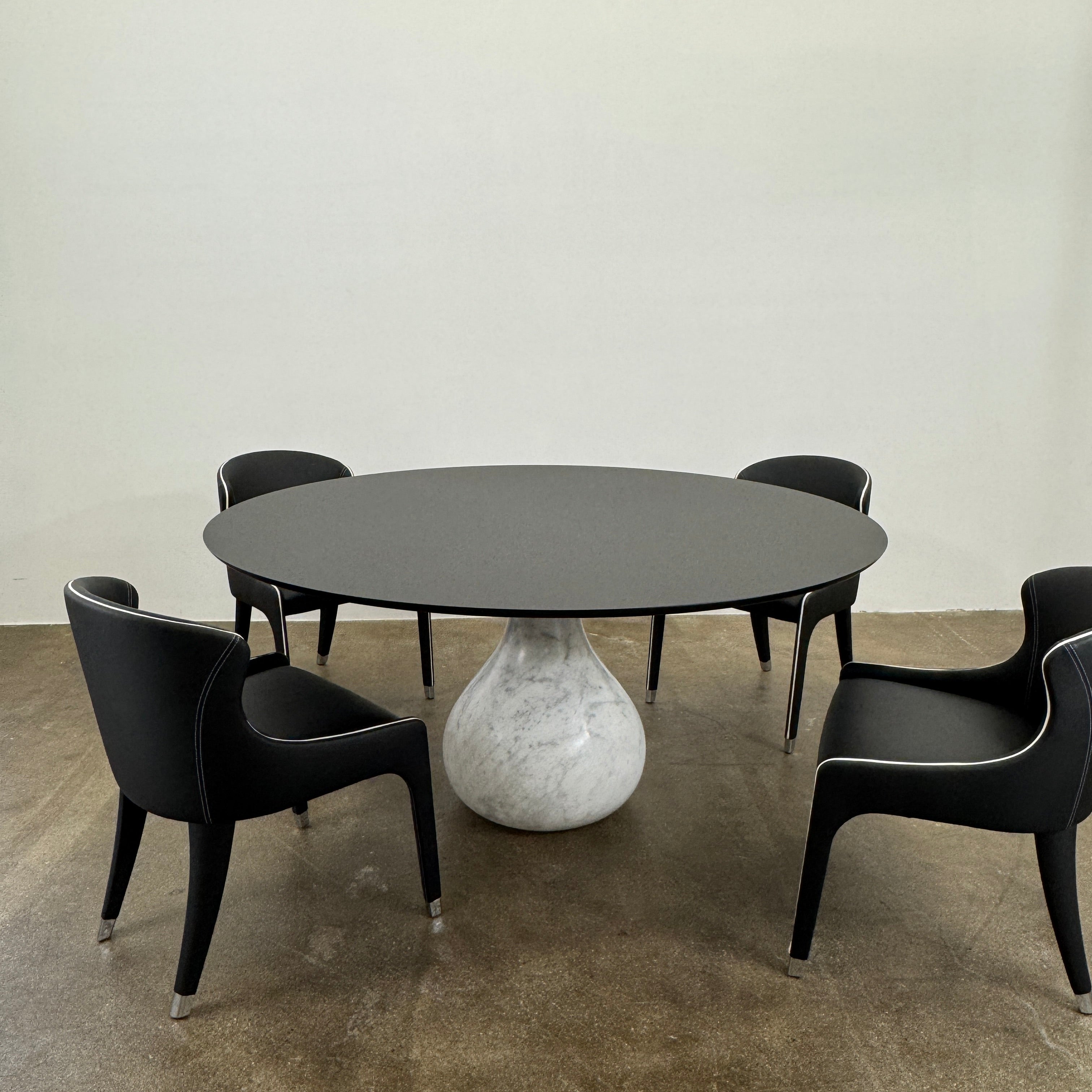 The Roche Bobois Aqua Round Table features a sleek black top and a teardrop-shaped white marble base, blending elegance and modern style—an iconic design by Roche Bobois, shown here against a plain white background.
