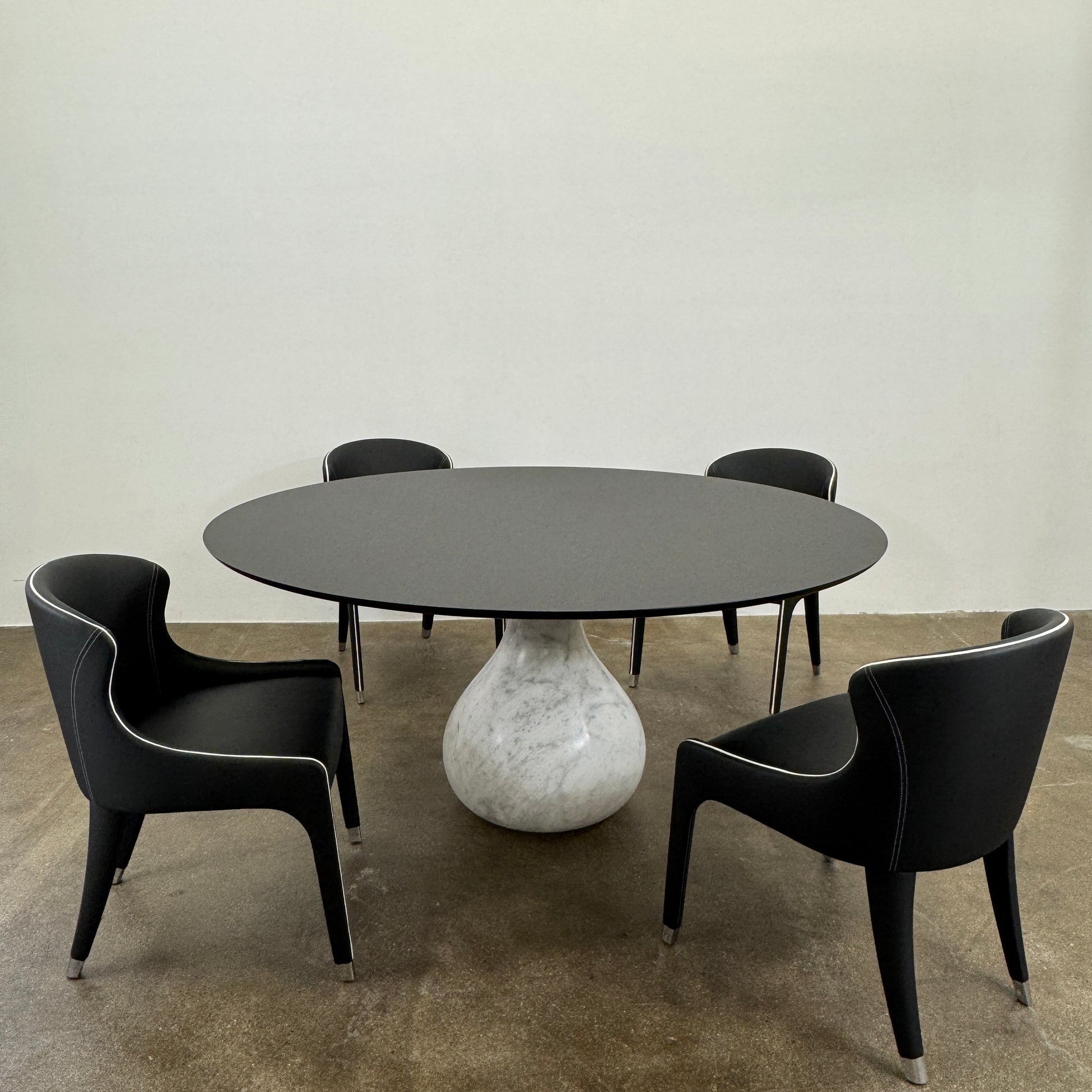 The Roche Bobois Aqua Round Table features a sleek black top and a teardrop-shaped white marble base, blending elegance and modern style—an iconic design by Roche Bobois, shown here against a plain white background.