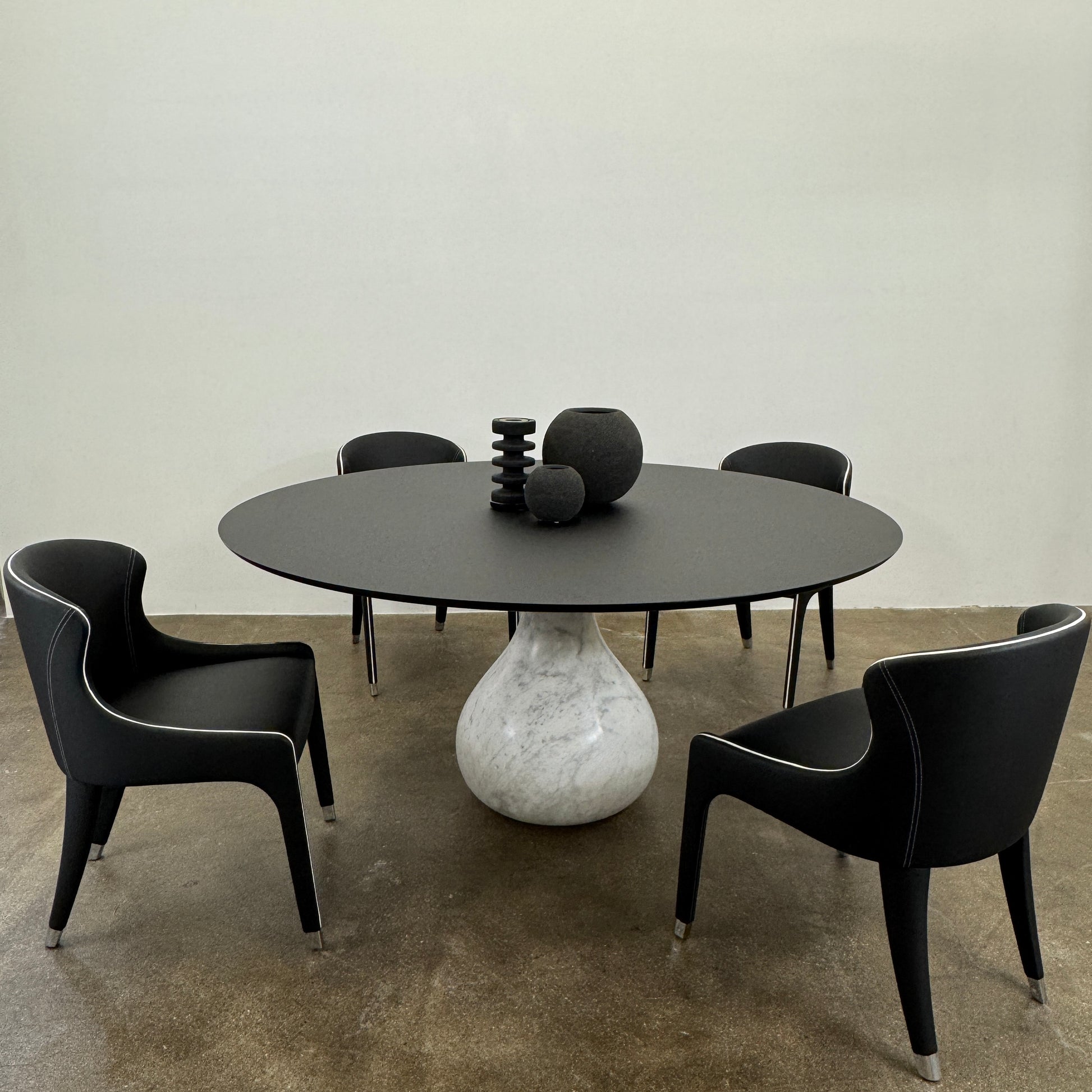 The Roche Bobois Aqua Round Table features a sleek black top and a teardrop-shaped white marble base, blending elegance and modern style—an iconic design by Roche Bobois, shown here against a plain white background.