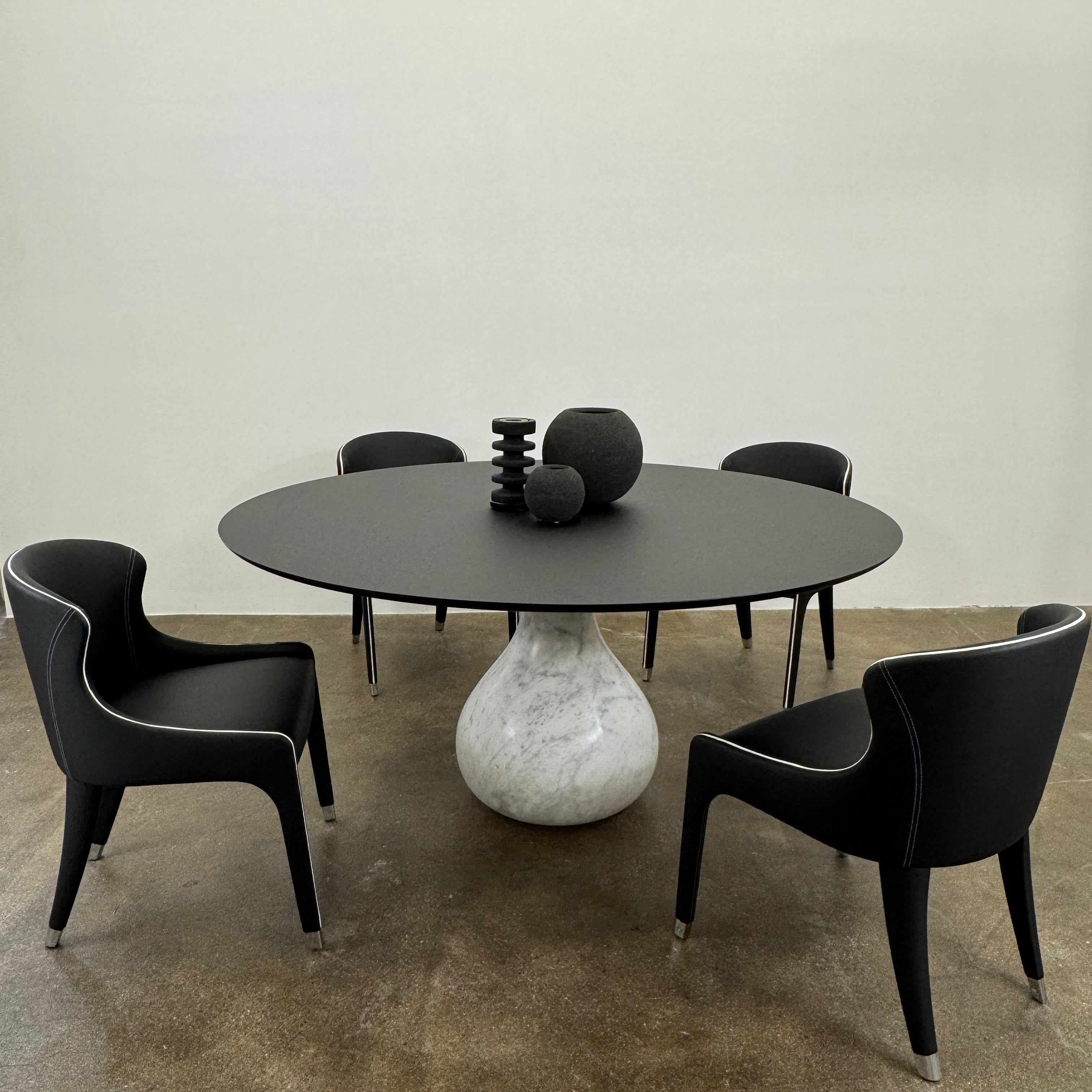 The Roche Bobois Aqua Round Table features a sleek black top and a teardrop-shaped white marble base, blending elegance and modern style—an iconic design by Roche Bobois, shown here against a plain white background.