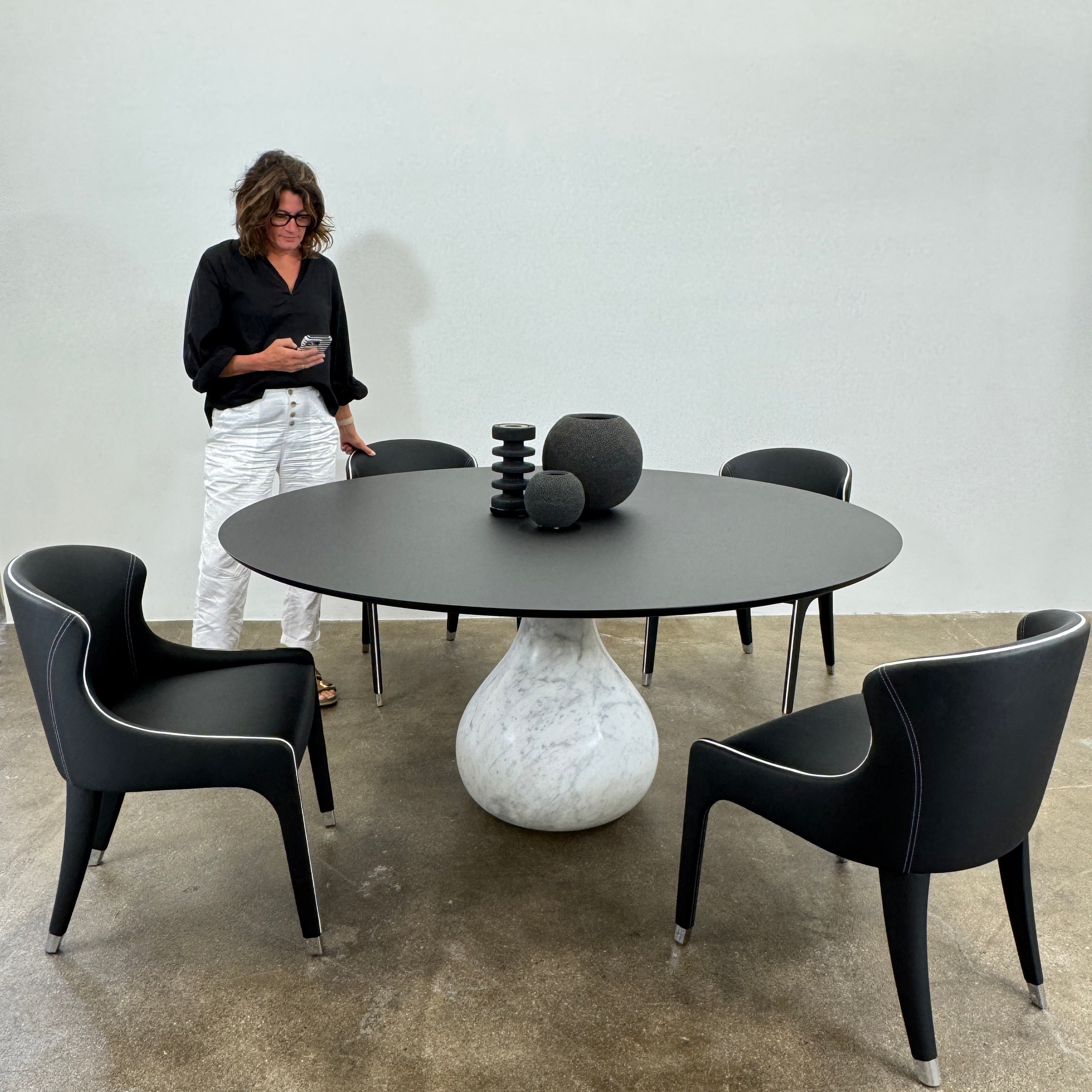 The Roche Bobois Aqua Round Table features a sleek black top and a teardrop-shaped white marble base, blending elegance and modern style—an iconic design by Roche Bobois, shown here against a plain white background.