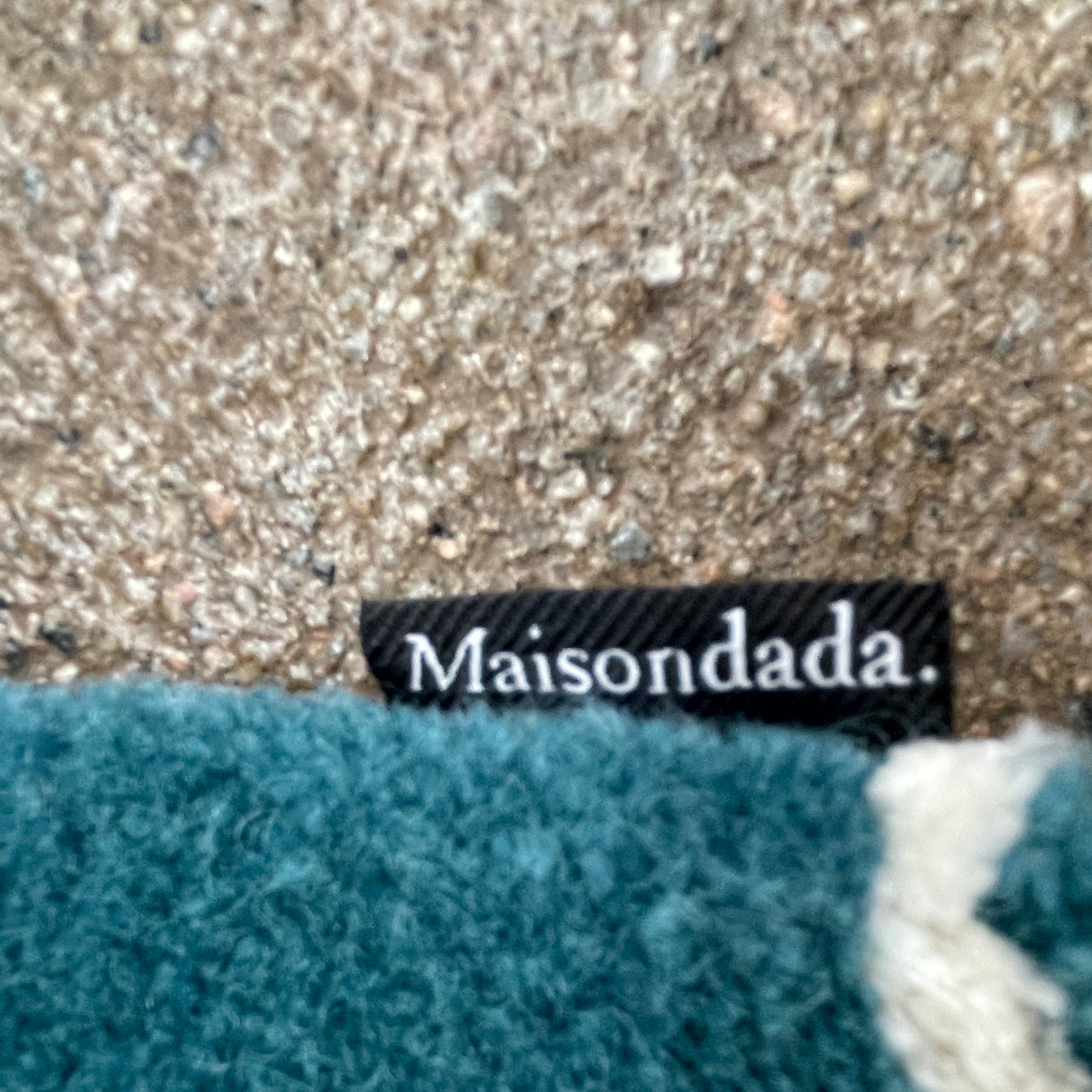 The Maison Dada Japanese Abstraction No5 Rug showcases a geometric pattern with a striking central circle in orange, green, and cream. A smaller purple circle enhances the design, complemented by a white star pattern on a green background reminiscent of Japanese abstraction.