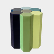 The Delcourt Collection MUC 7 Side Tables feature interconnected ceramic hexagons in green, blue, brown, and gray on a light gray background. Echoing Christophe Delcourt's design ethos, these versatile pieces enhance any space with style and functionality.