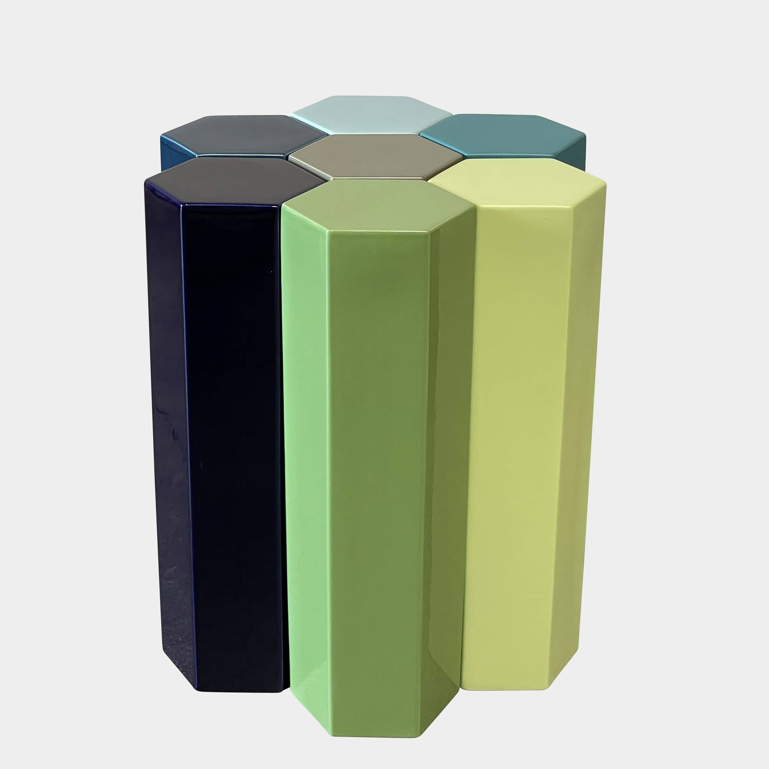 The Delcourt Collection MUC 7 Side Tables feature interconnected ceramic hexagons in green, blue, brown, and gray on a light gray background. Echoing Christophe Delcourt's design ethos, these versatile pieces enhance any space with style and functionality.