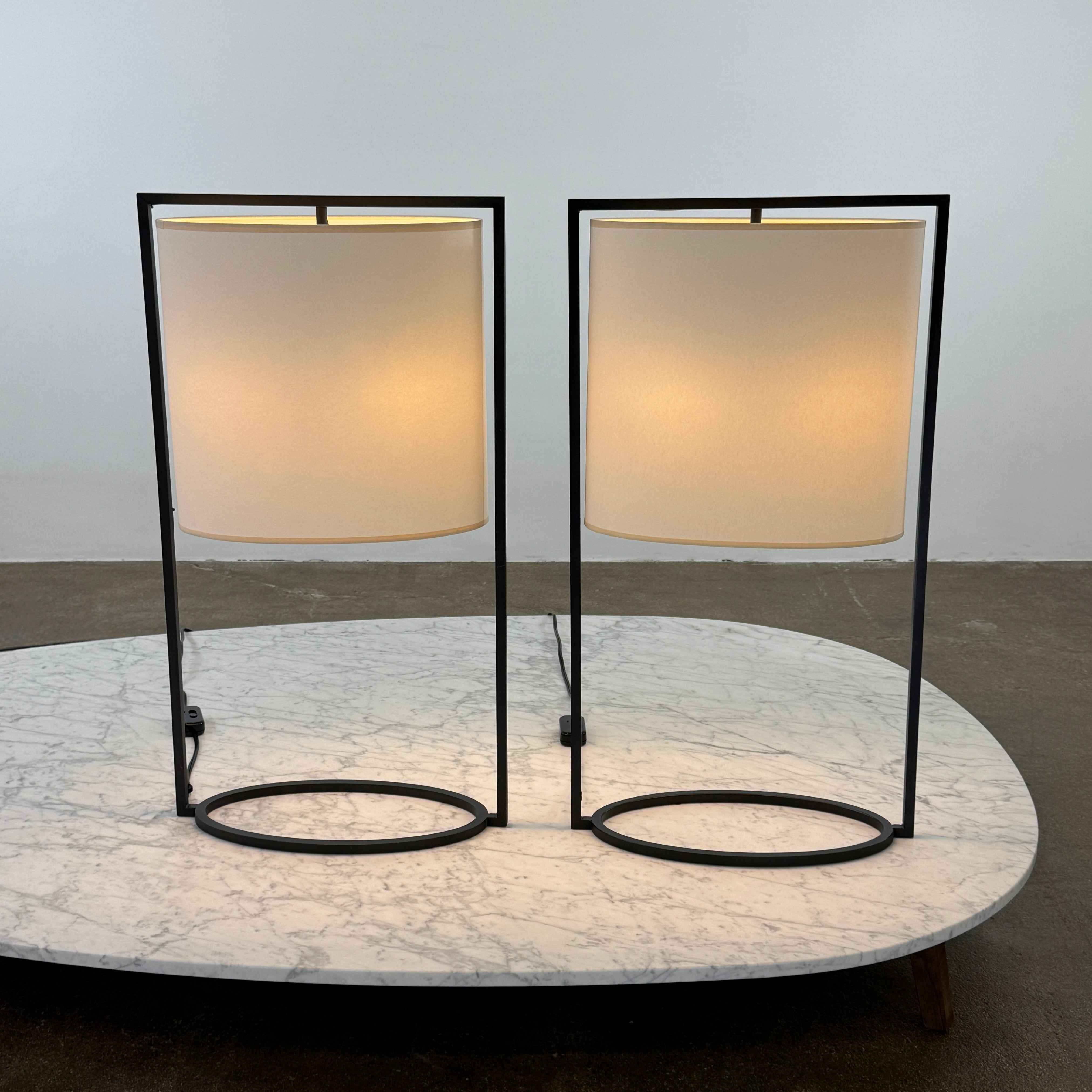 The Holly Hunt Pattern Table Lamp by Holly Hunt features a white cylindrical shade and black metal frame, offering modern style and dimmable lighting—perfect as a stylish reading lamp on any white background.