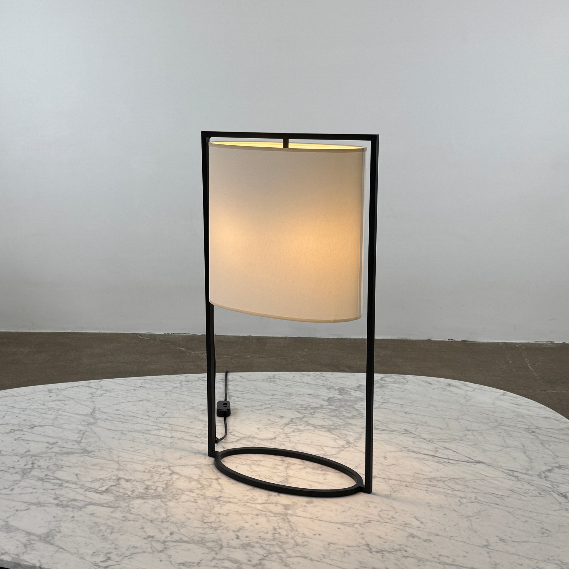 The Holly Hunt Pattern Table Lamp by Holly Hunt features a white cylindrical shade and black metal frame, offering modern style and dimmable lighting—perfect as a stylish reading lamp on any white background.