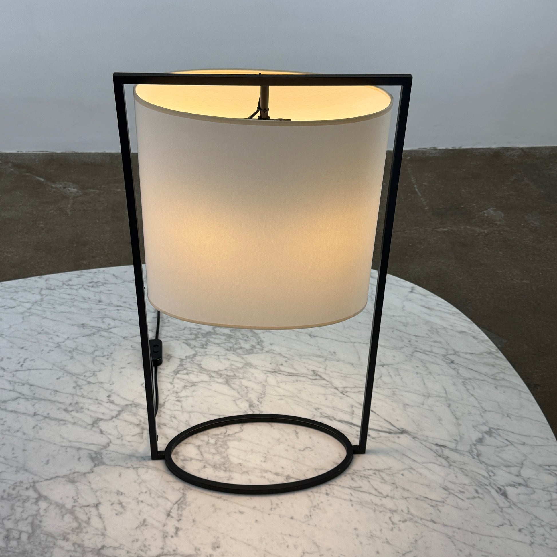 The Holly Hunt Pattern Table Lamp by Holly Hunt features a white cylindrical shade and black metal frame, offering modern style and dimmable lighting—perfect as a stylish reading lamp on any white background.