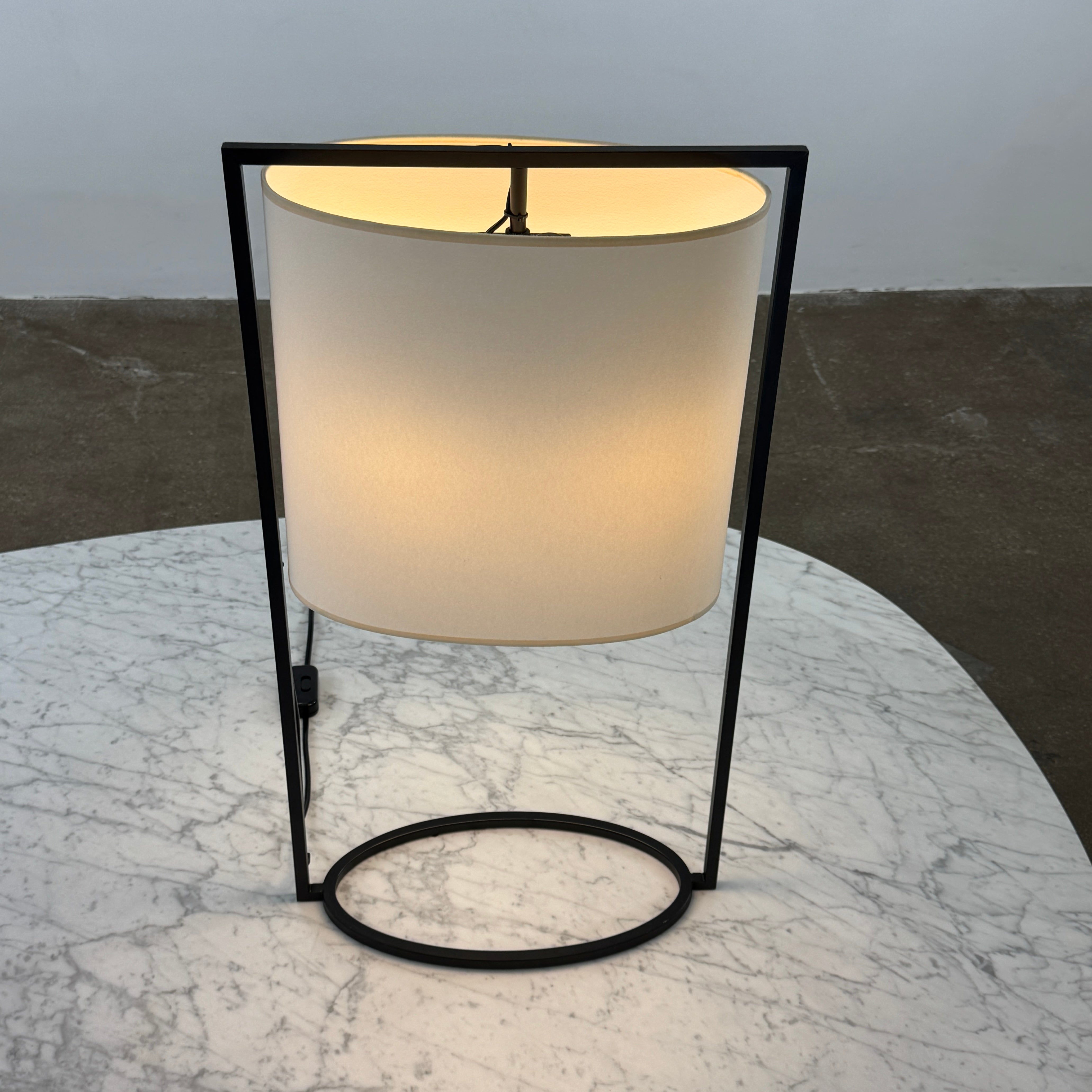 The Holly Hunt Pattern Table Lamp by Holly Hunt features a white cylindrical shade and black metal frame, offering modern style and dimmable lighting—perfect as a stylish reading lamp on any white background.