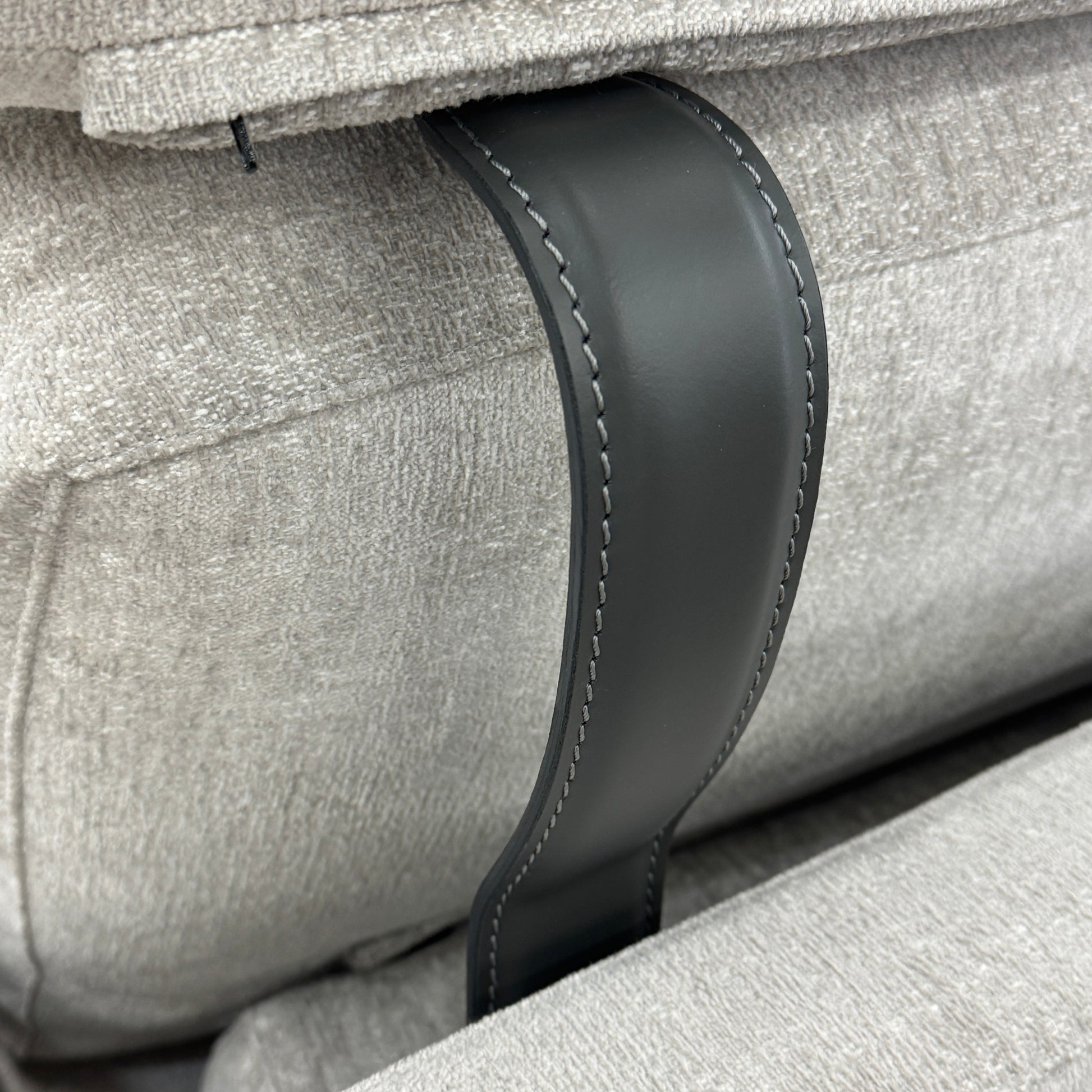 The Poliform Mondrian 2 piece Sectional Sofa with Headrests by Poliform, in light beige, features modern minimalist style with adjustable headrests and a black throw pillow, set on a concrete floor against a plain white wall.