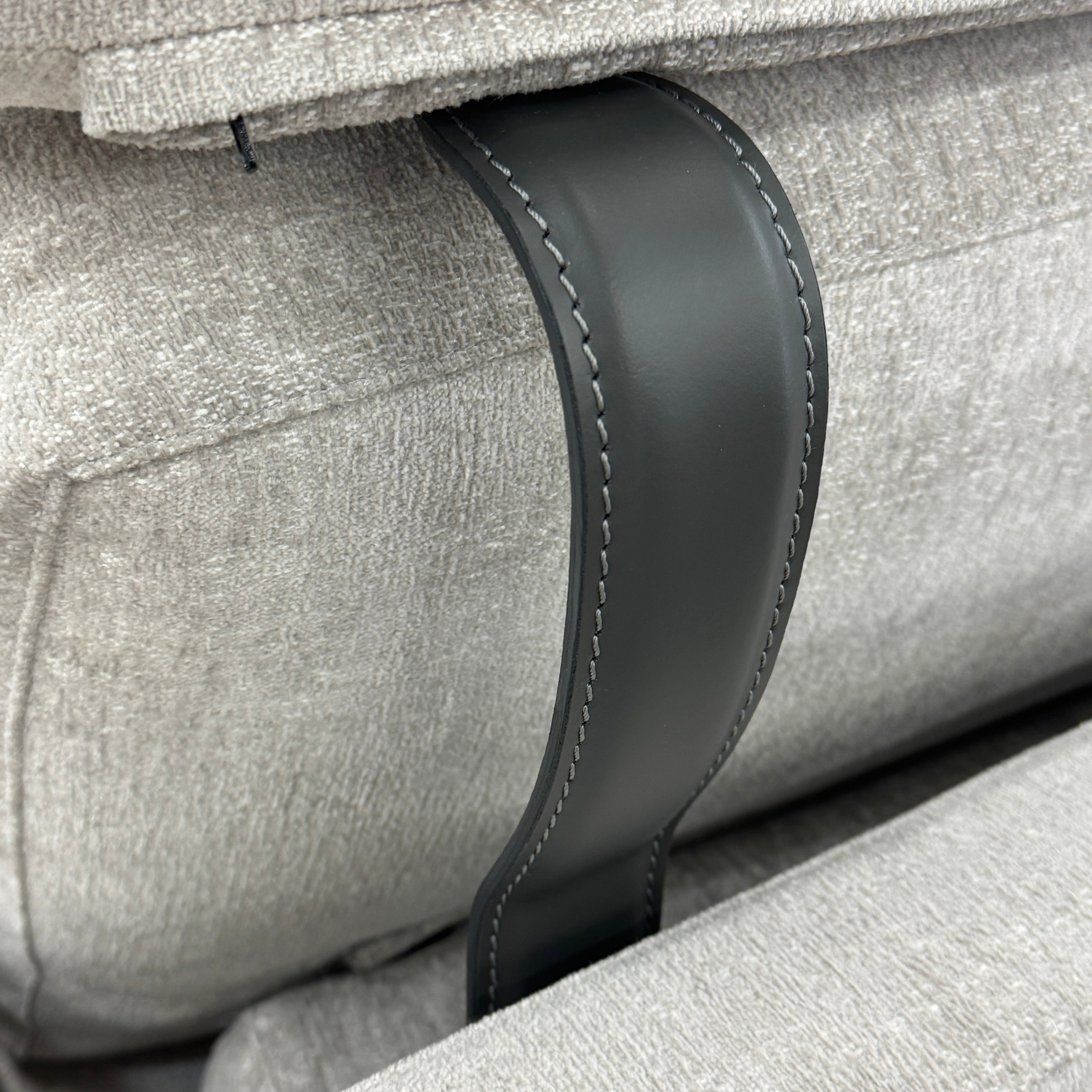 The Poliform Mondrian 2 piece Sectional Sofa with Headrests by Poliform, in light beige, features modern minimalist style with adjustable headrests and a black throw pillow, set on a concrete floor against a plain white wall.