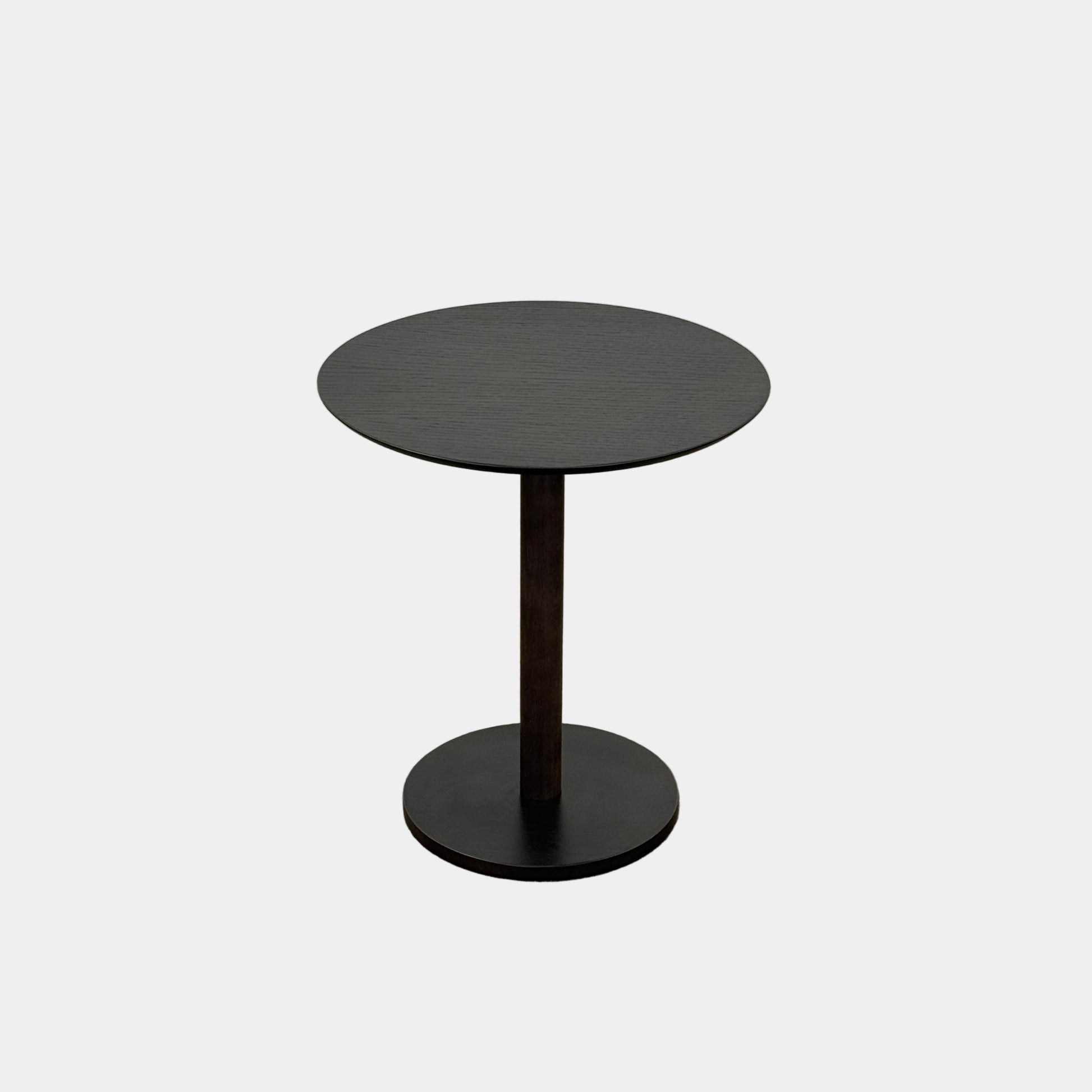 The Maruni Hiroshima Side Table by Maruni features a small, round black oak top and a single central pedestal base, shown against a plain light gray background.