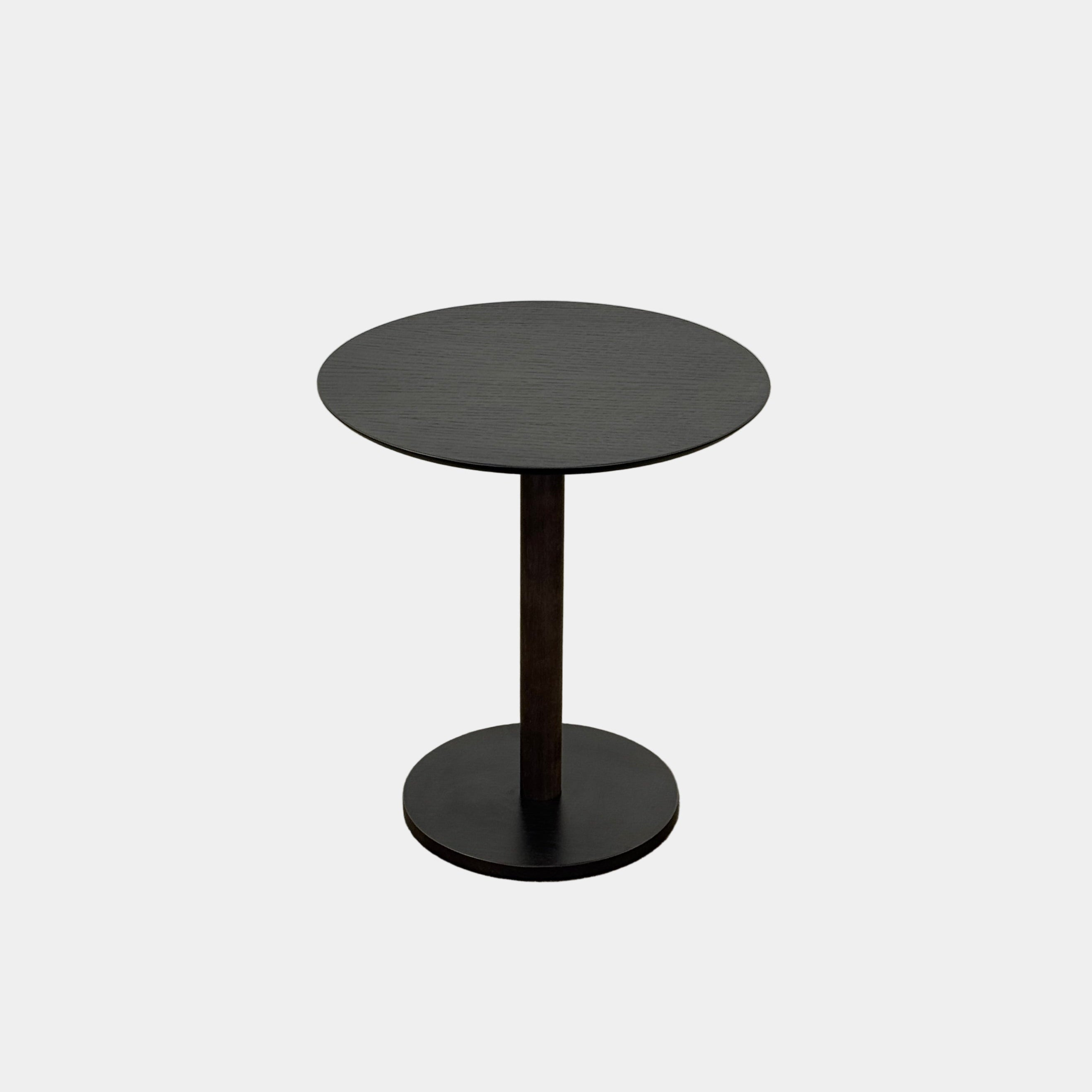 The Maruni Hiroshima Side Table by Maruni features a small, round black oak top and a single central pedestal base, shown against a plain light gray background.