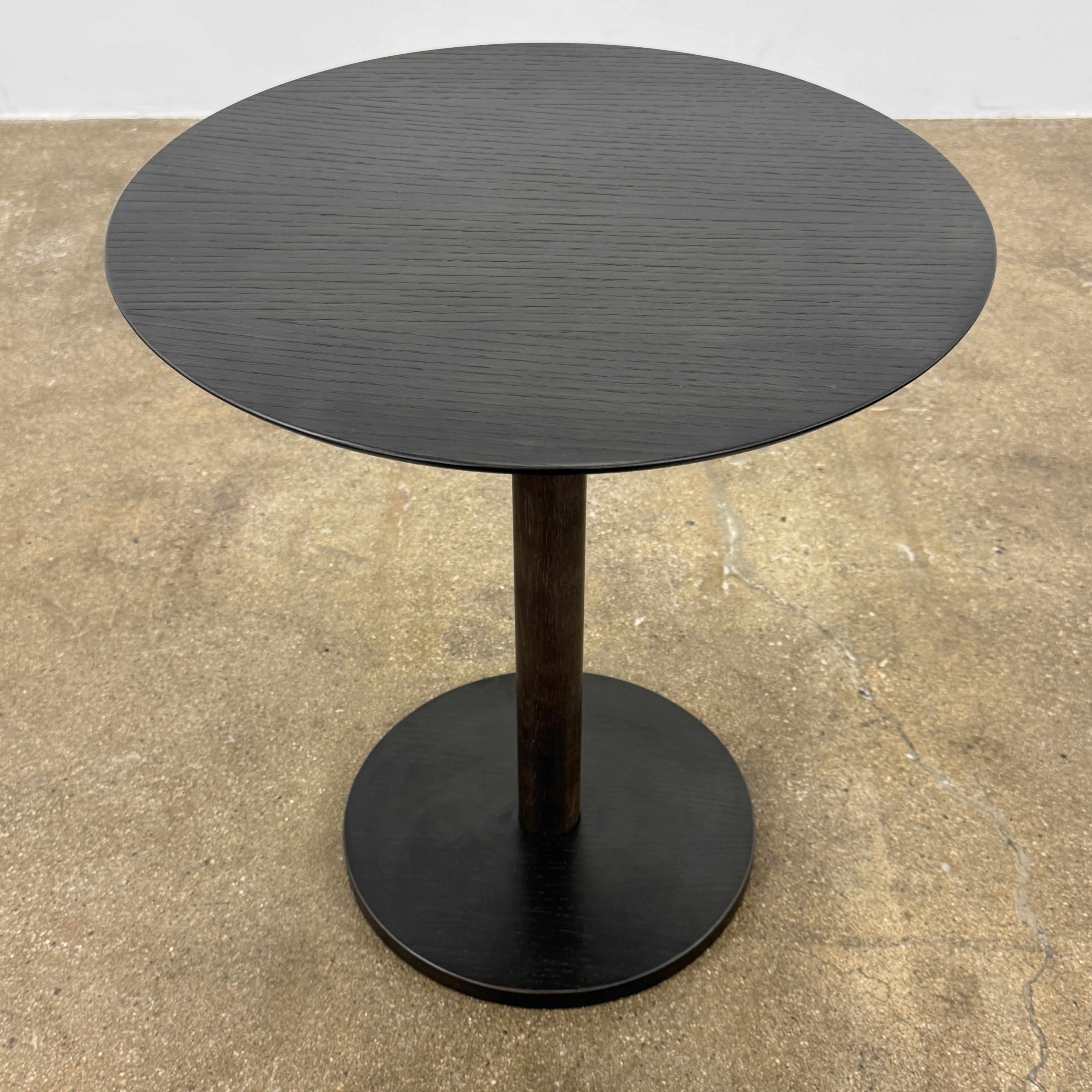 The Maruni Hiroshima Side Table by Maruni features a small, round black oak top and a single central pedestal base, shown against a plain light gray background.